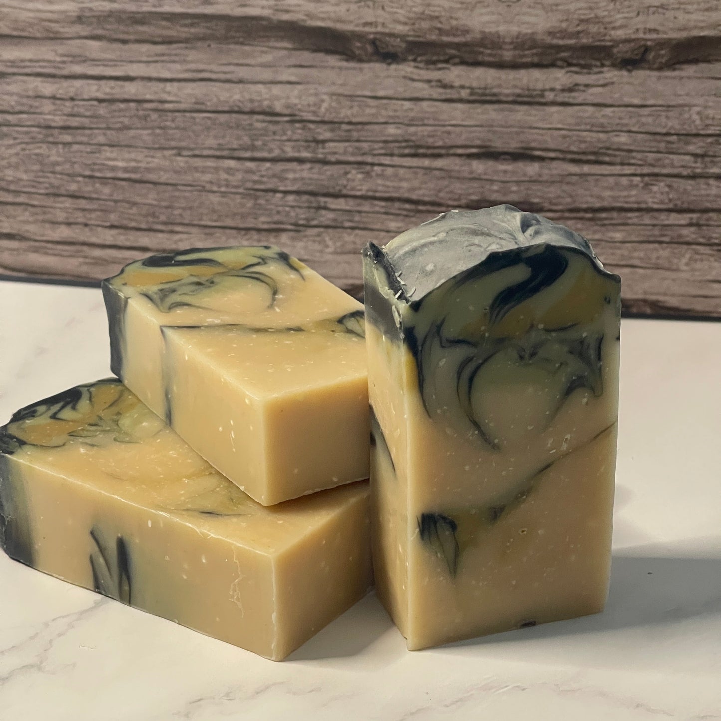 Three marbled soap bars on a marble surface with a wooden background