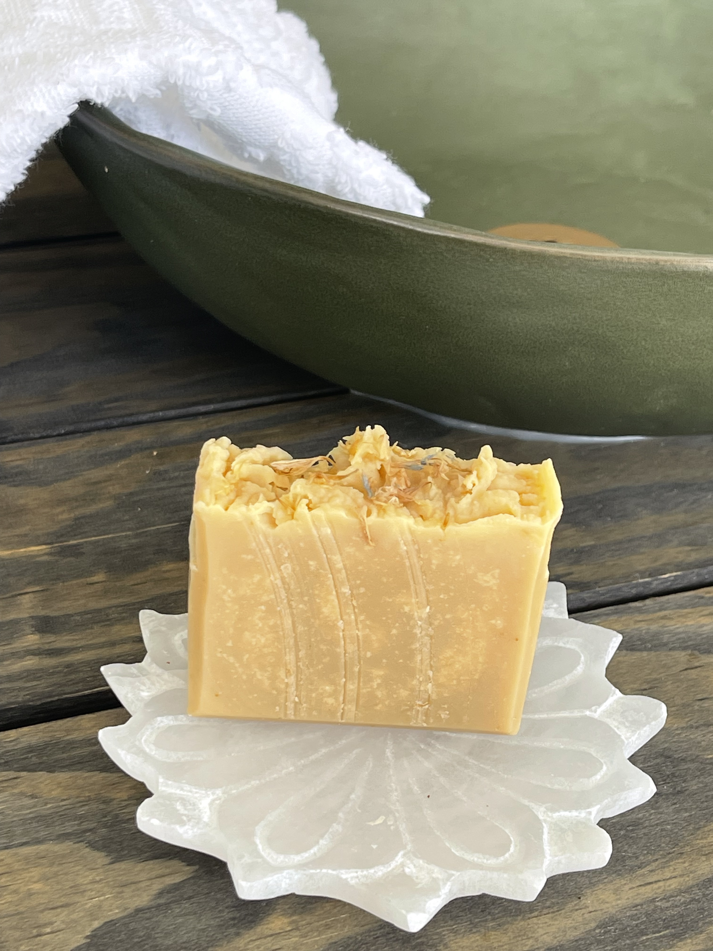 Bar of soap on a decorative soap dish with a green bowl in the background