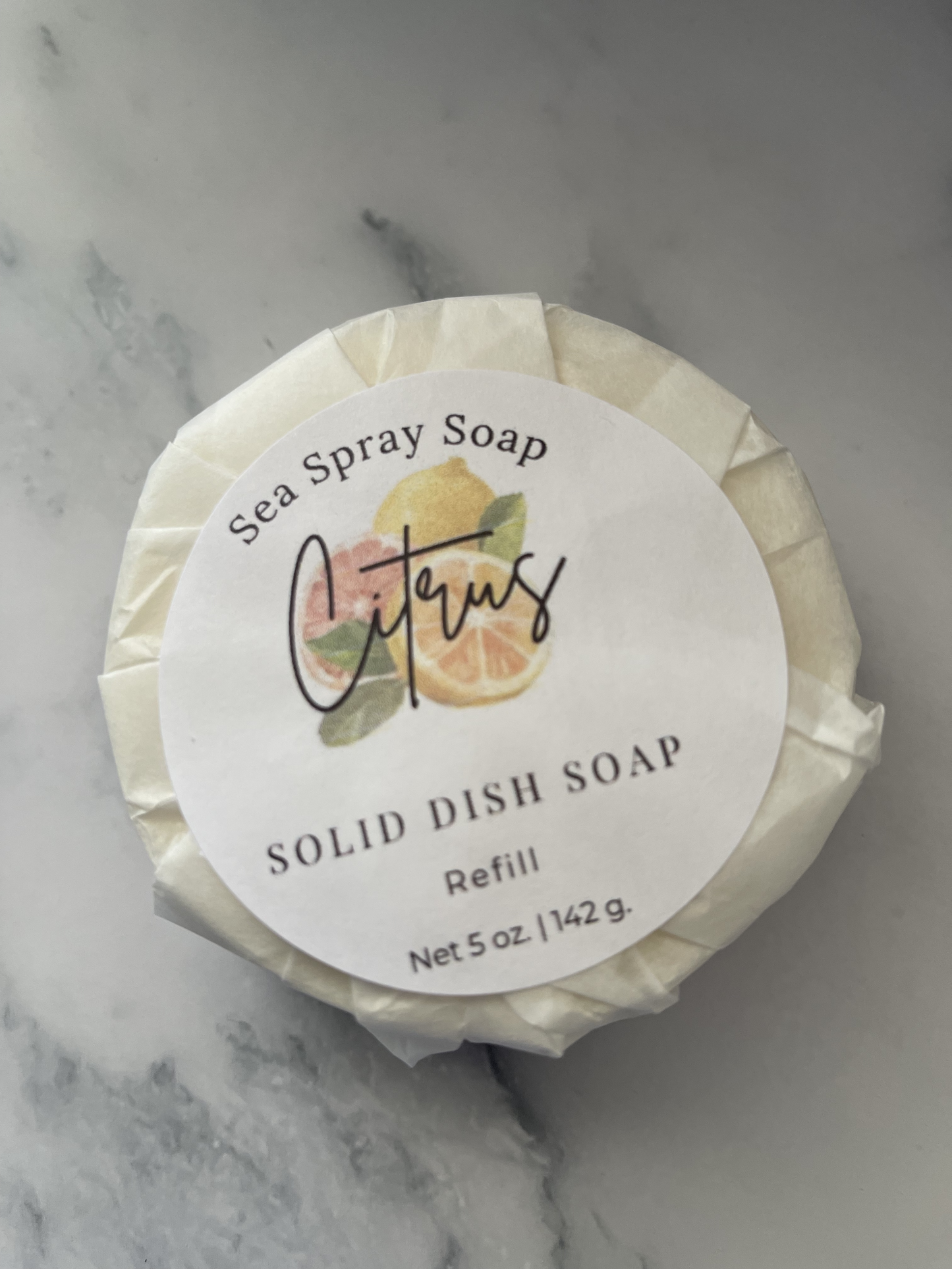 Solid dish soap refill with a label on a marble surface