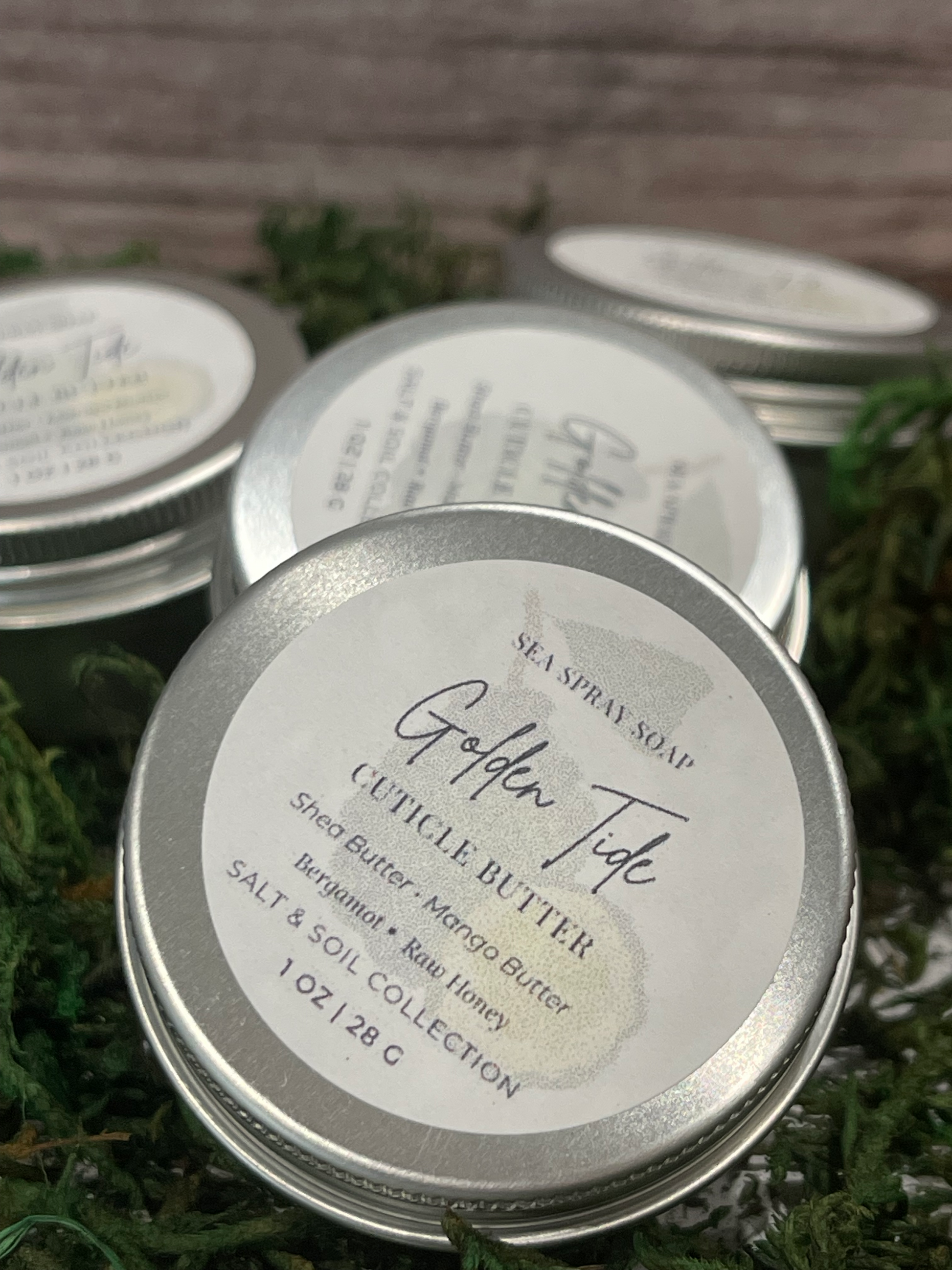 Golden Tide Cuticle Butter Tins on top of some moss