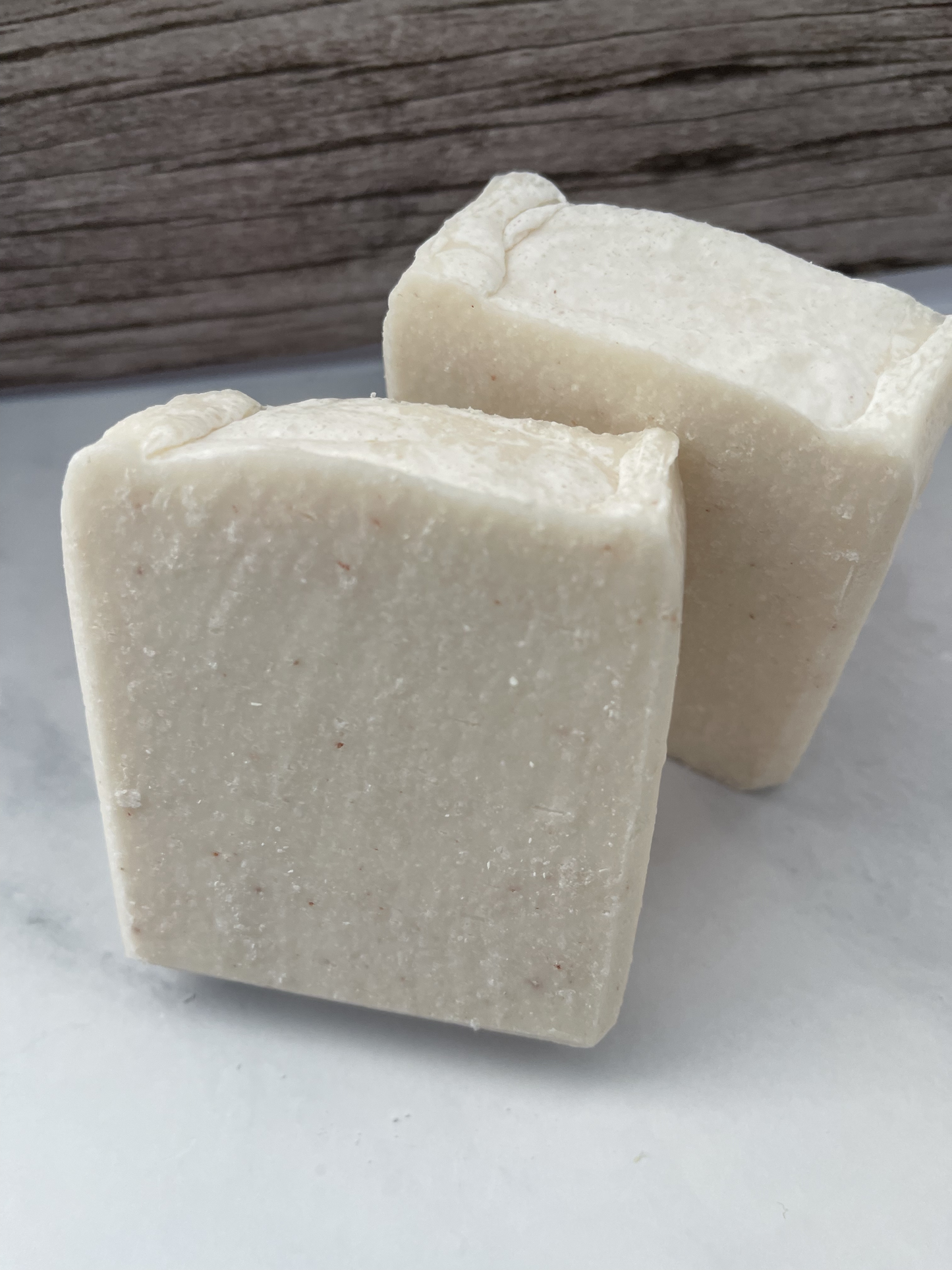 Two blocks of natural soap on a light surface with a wooden background