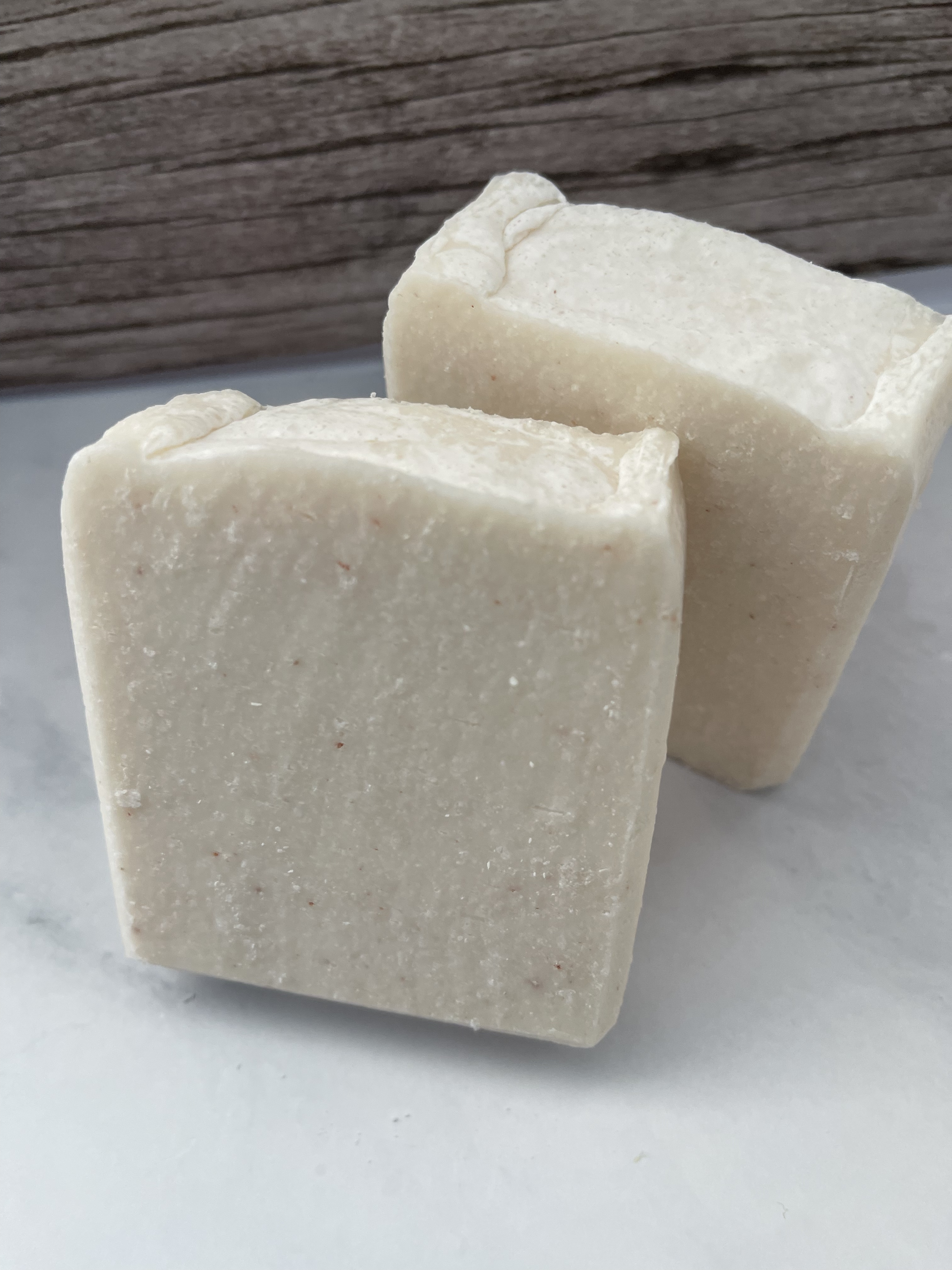 Two blocks of natural soap on a light surface with a wooden background