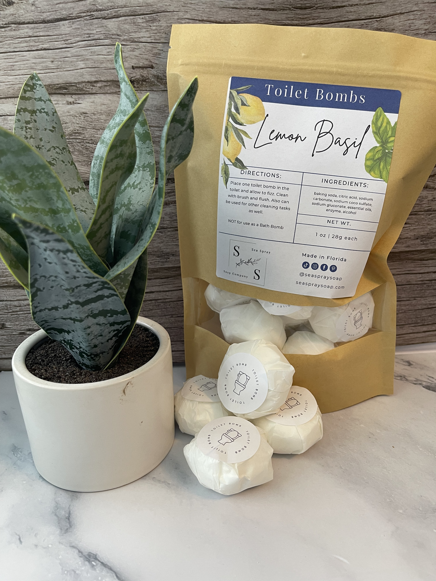 Bag of Lemon Basil toilet bombs with a potted plant on a marble surface