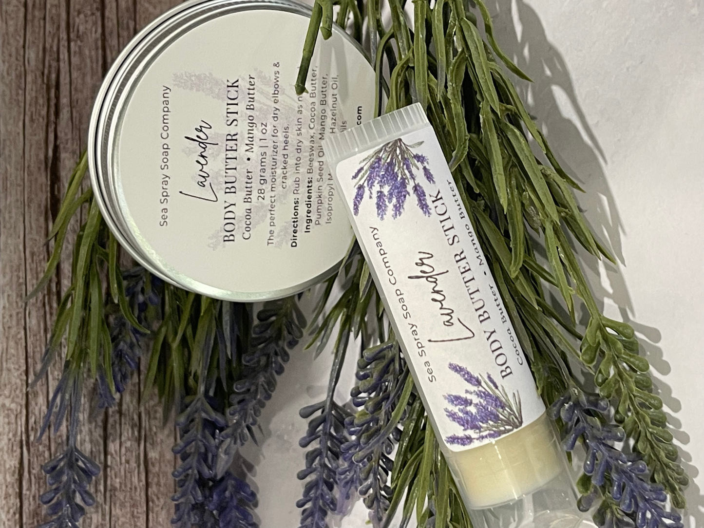 Lavender body butter stick and tin with lavender sprigs on a wooden surface