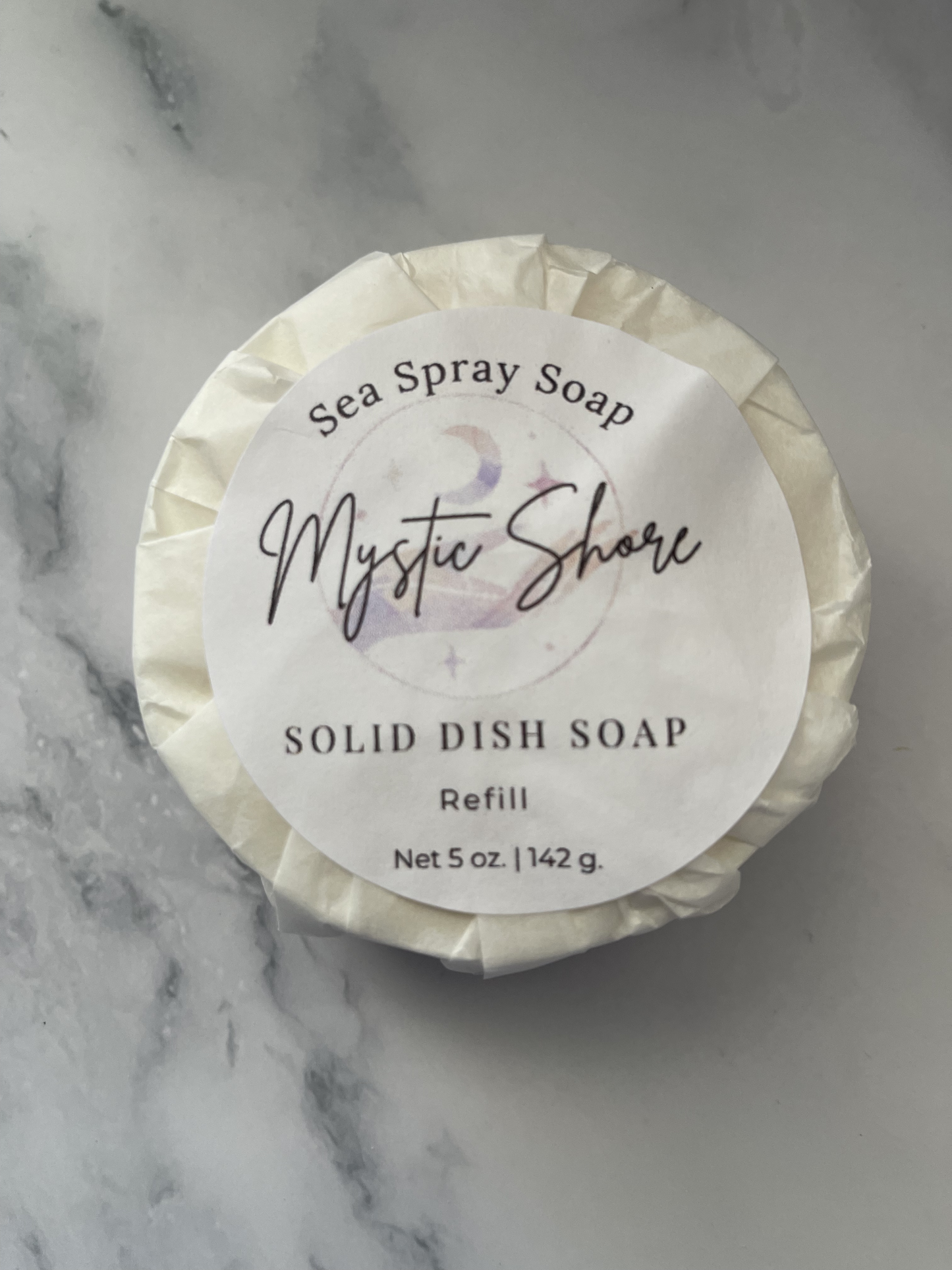 Solid dish soap refill labeled 'Mystic Shore' on a marble background