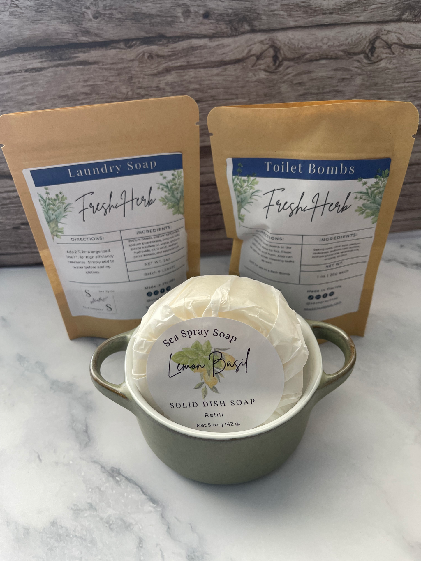 Two containers of Fresh Herb soap on a marble surface with a wooden background.