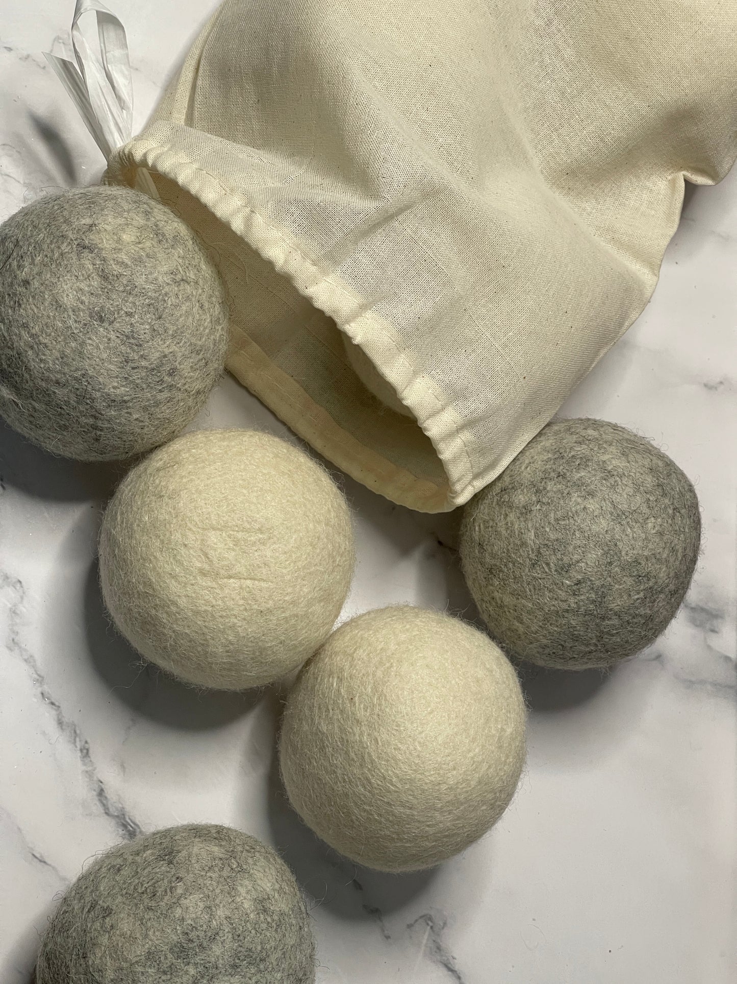 Set of natural laundry balls on a marble surface with a beige cloth bag.