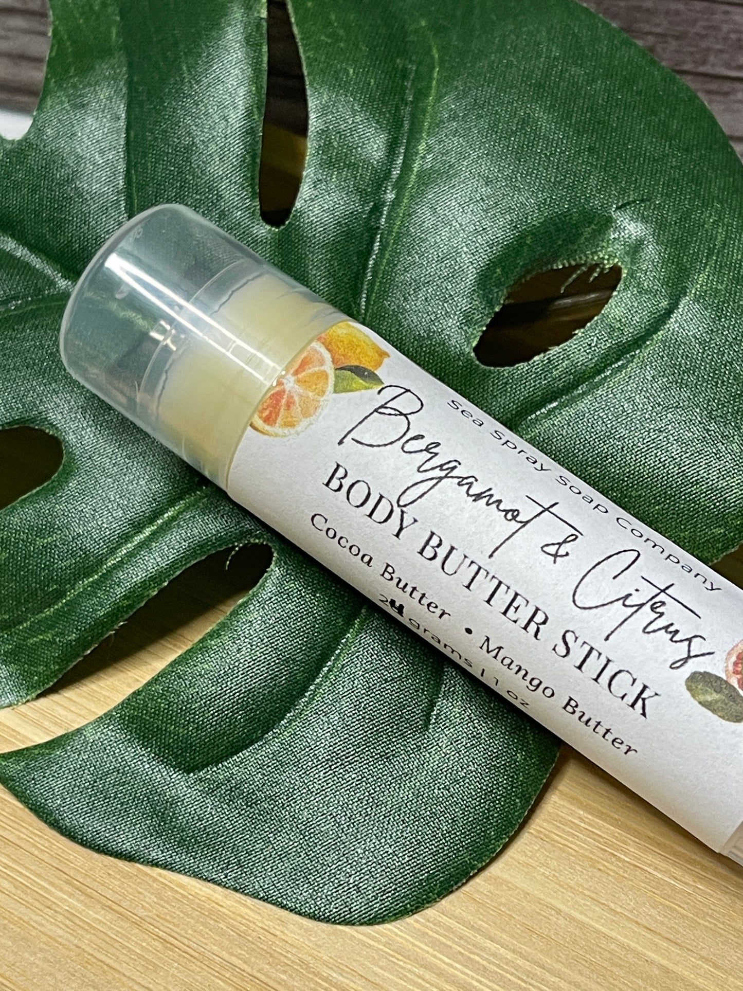 Body butter stick with packaging on a green leaf