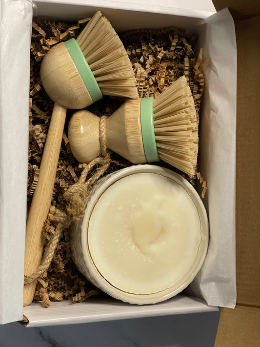 Set of cleaning brushes and a container in a box with brown bedding material.