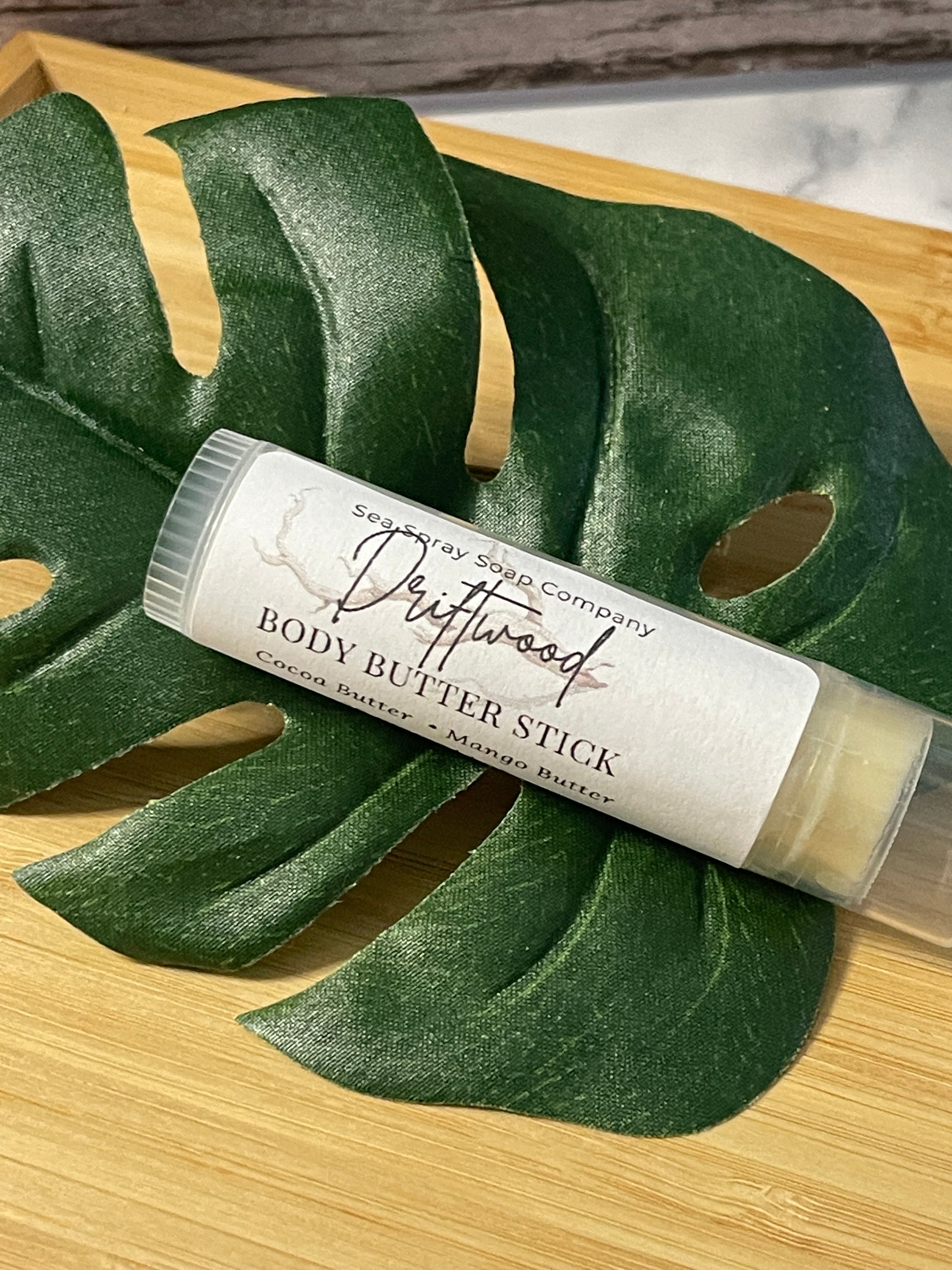 Body butter stick on a leaf with a wooden background
