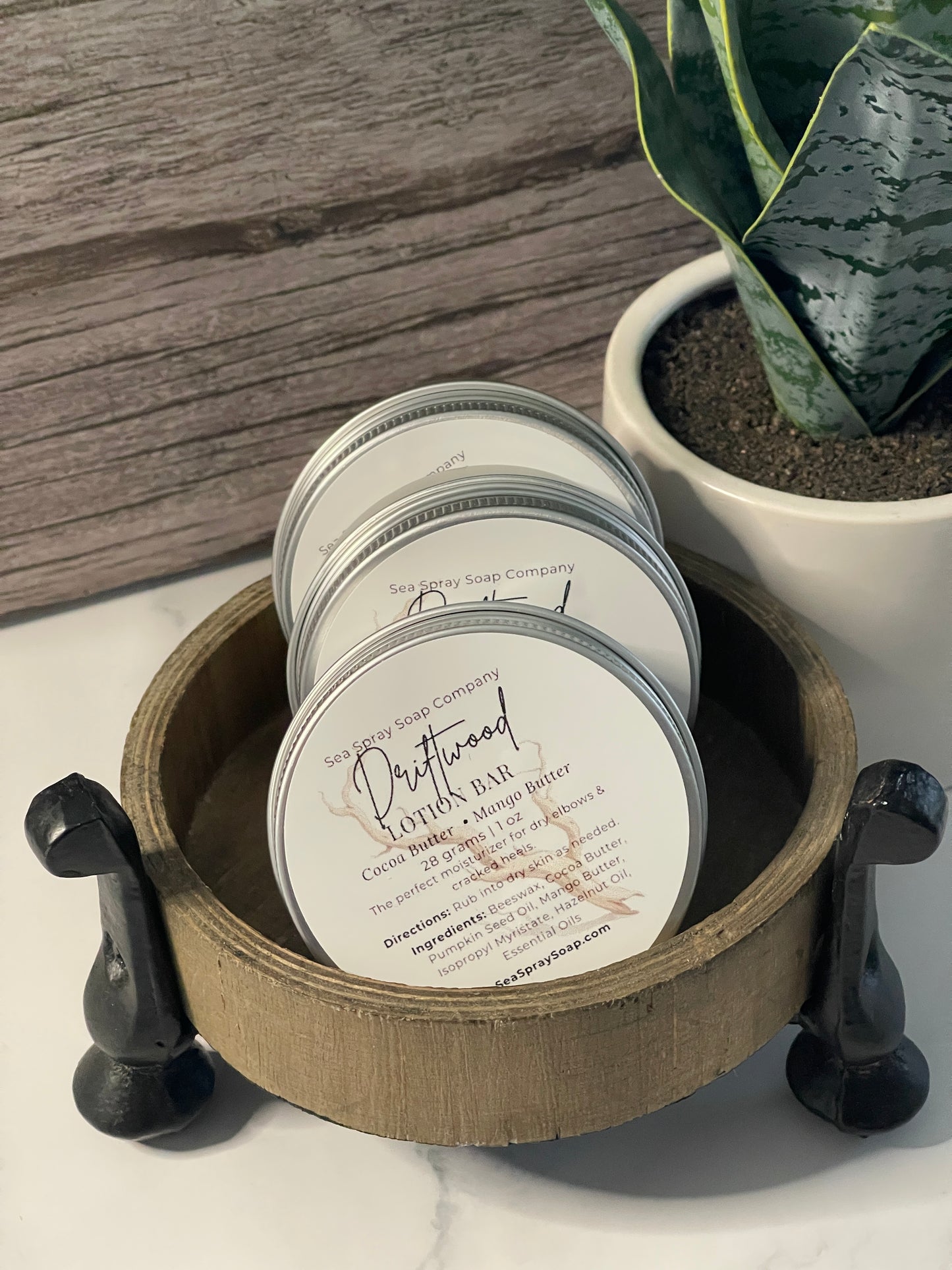 Jars of a product with a label on a wooden surface next to a plant