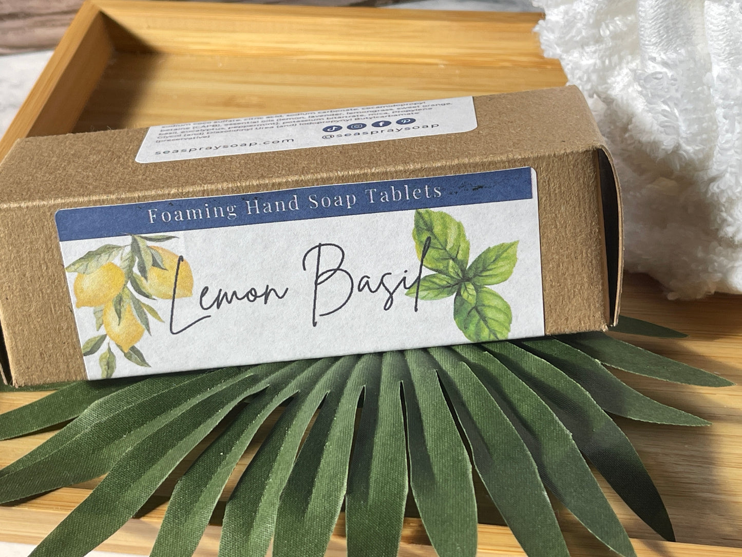 Box of Foaming Hand Soap Tablets with Lemon Basil flavor on a wooden surface with green leaves.