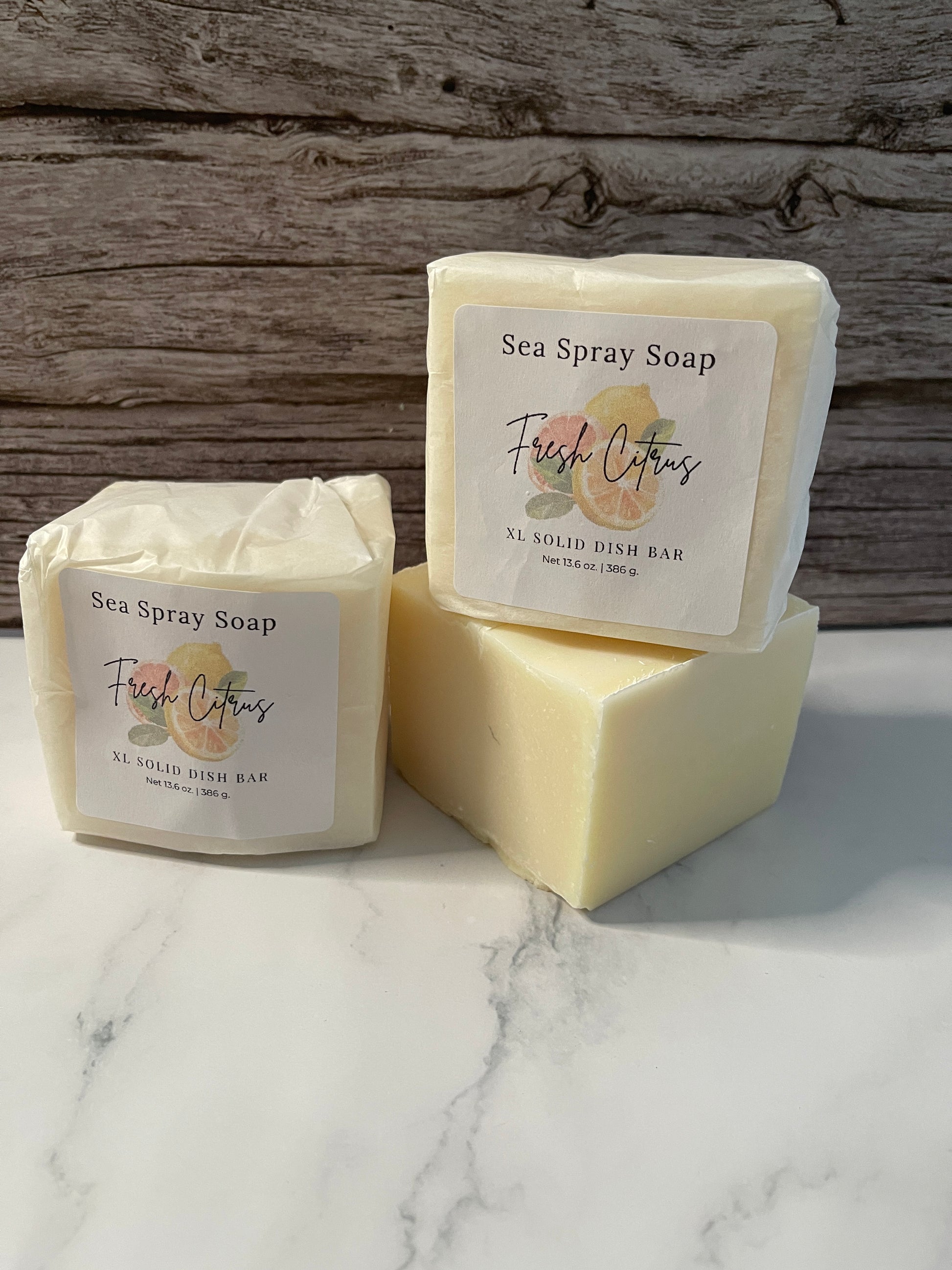 Three bars of soap with labels on a wooden and marble surface