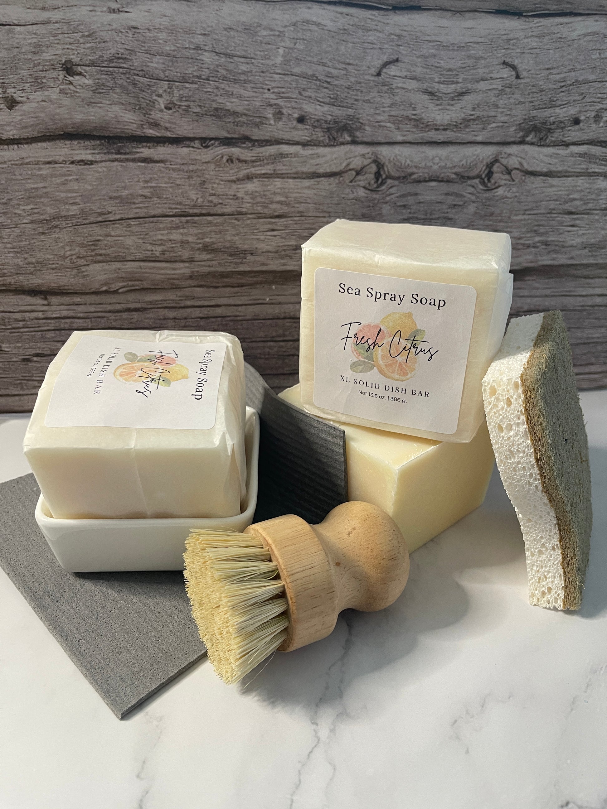 Two soap bars with labels and a brush on a wooden surface
