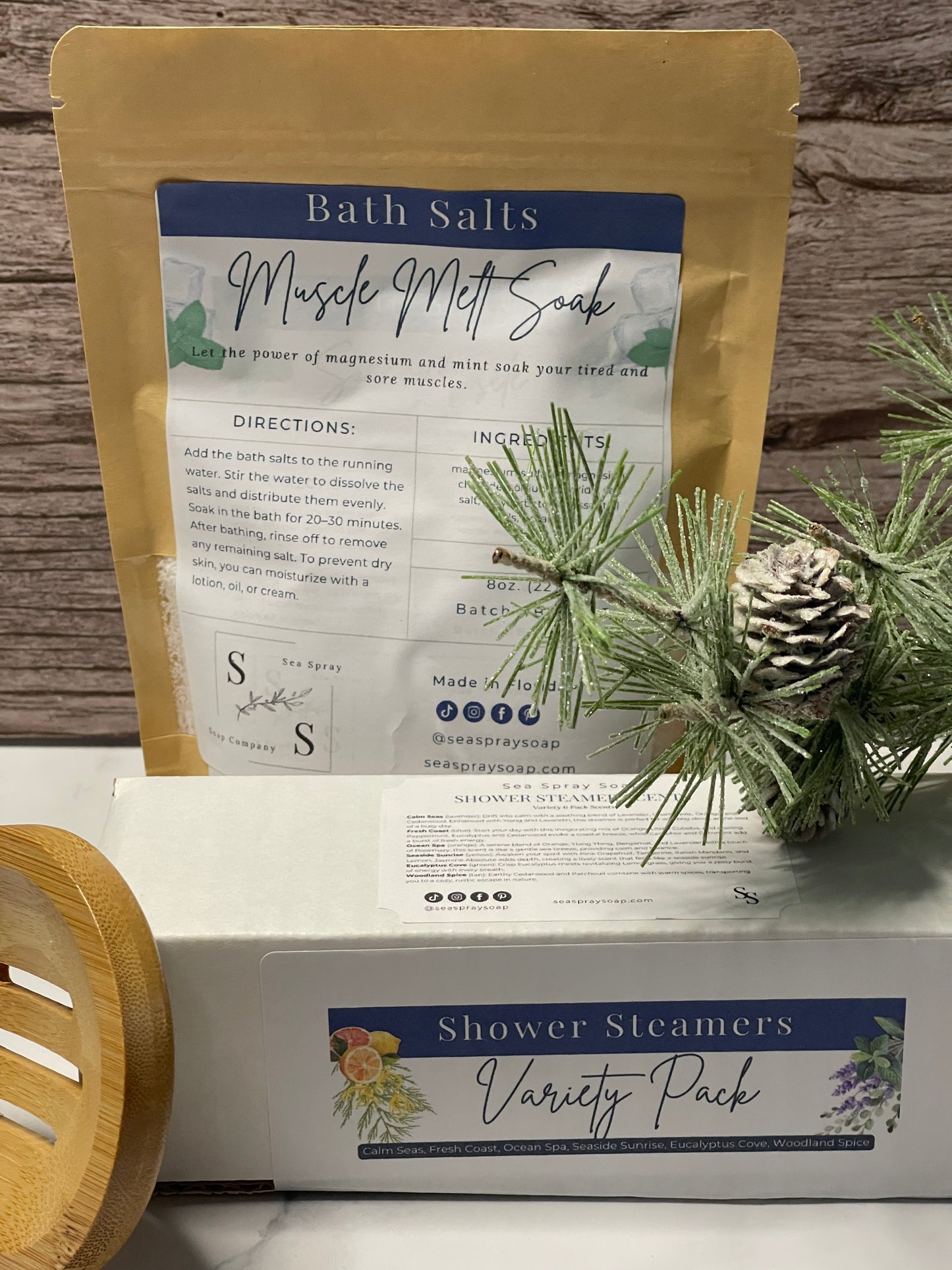 Bath salts package with a pine cone and greenery on a wooden surface