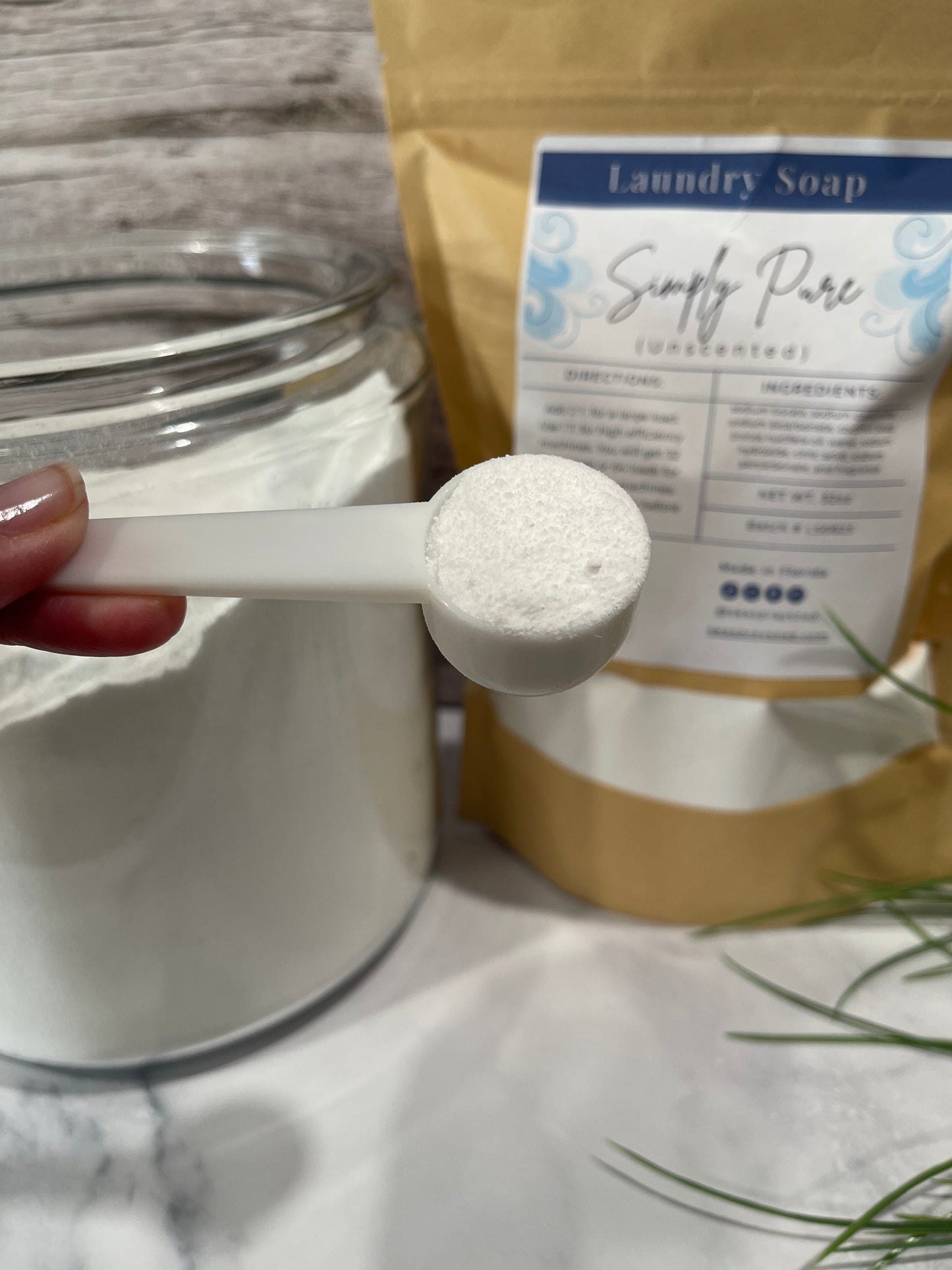 White measuring spoon held over a container with a label in the background