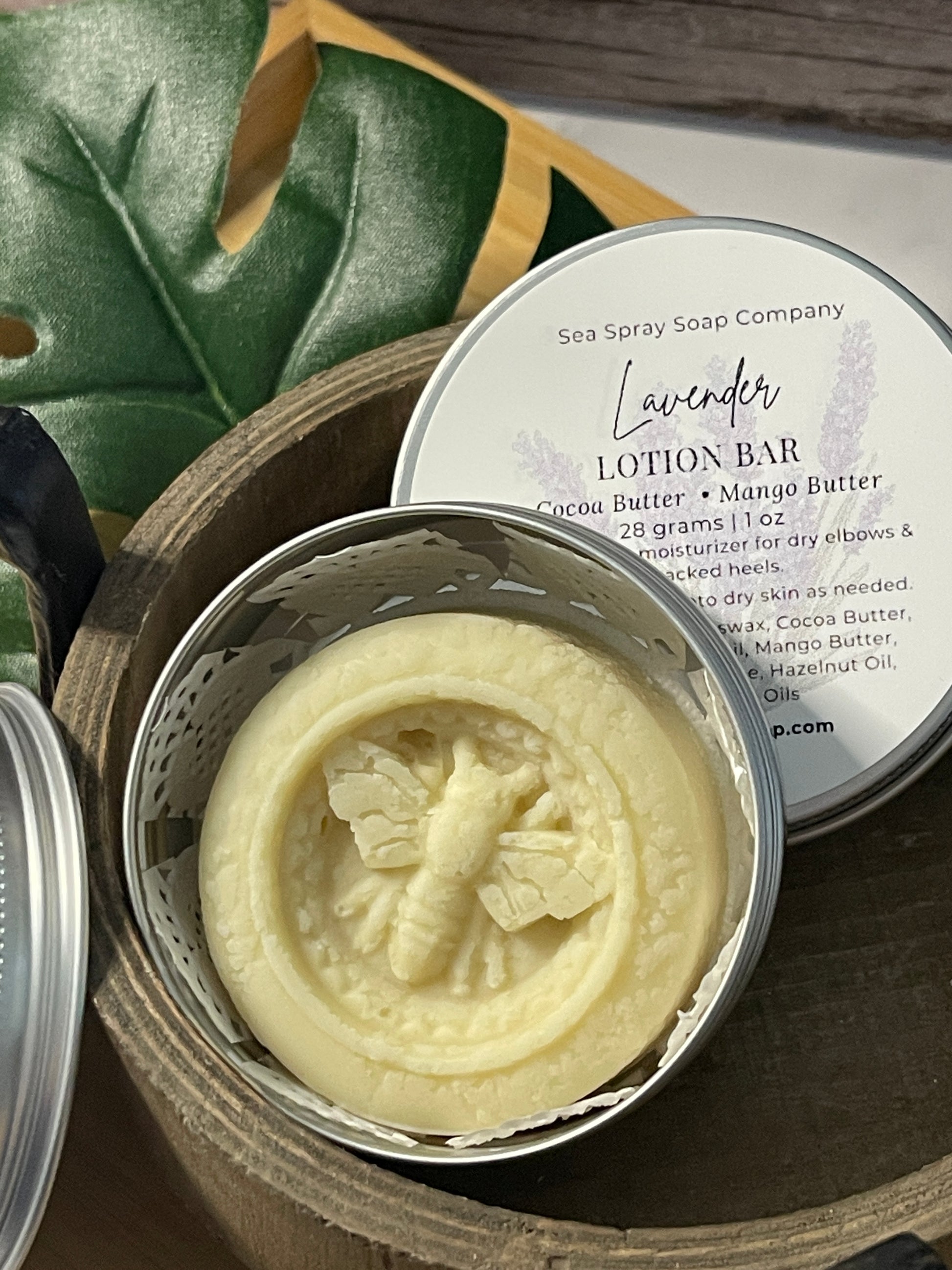 Lavender lotion bar in a wooden container with a leafy background
