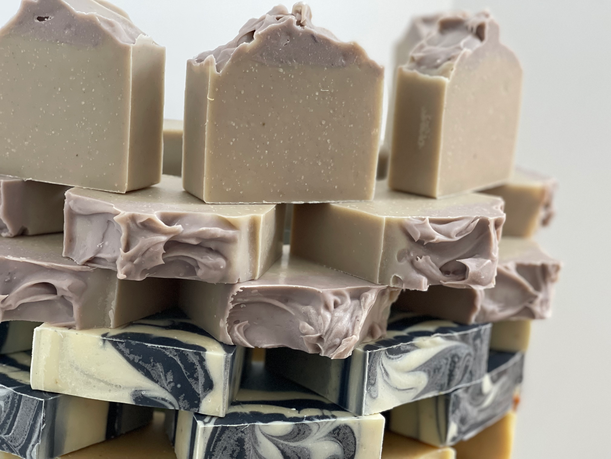 Stack of handmade soap bars with visible marbling on a light background