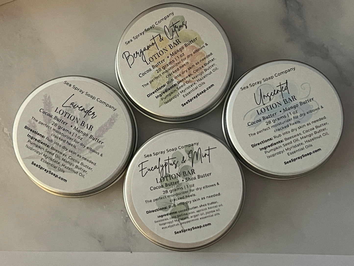 Five containers of Sea Spray Soap Company lotion bars on a marble surface.