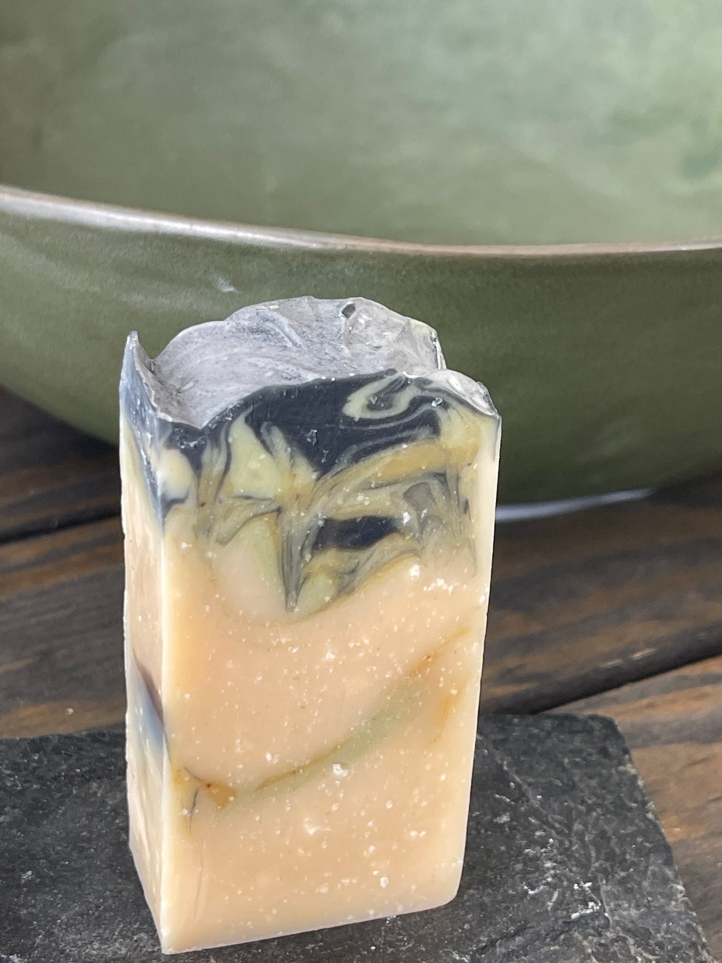Bar of soap with black and green swirls on a wooden surface