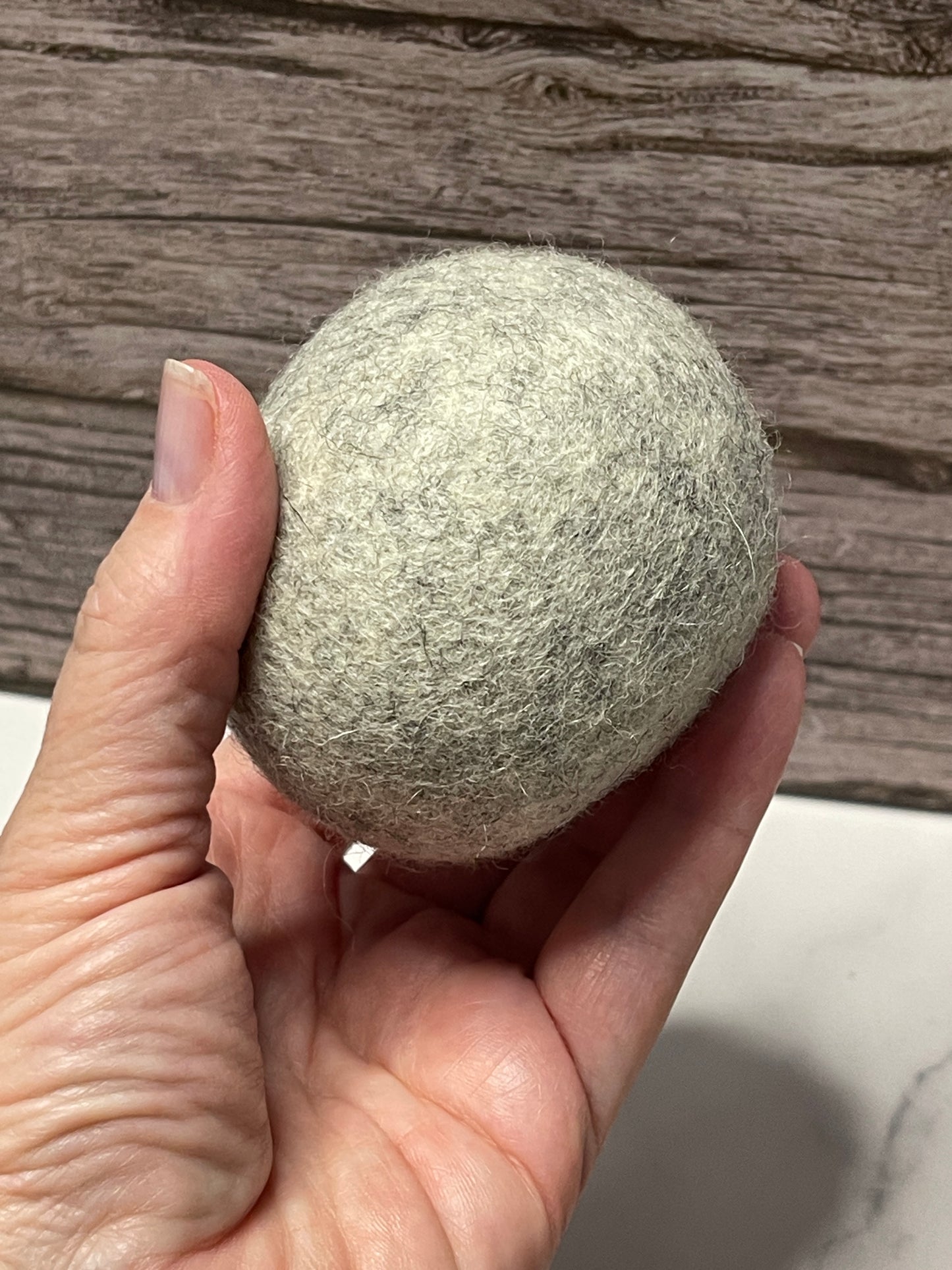 Hand holding a textured gray ball against a wooden surface