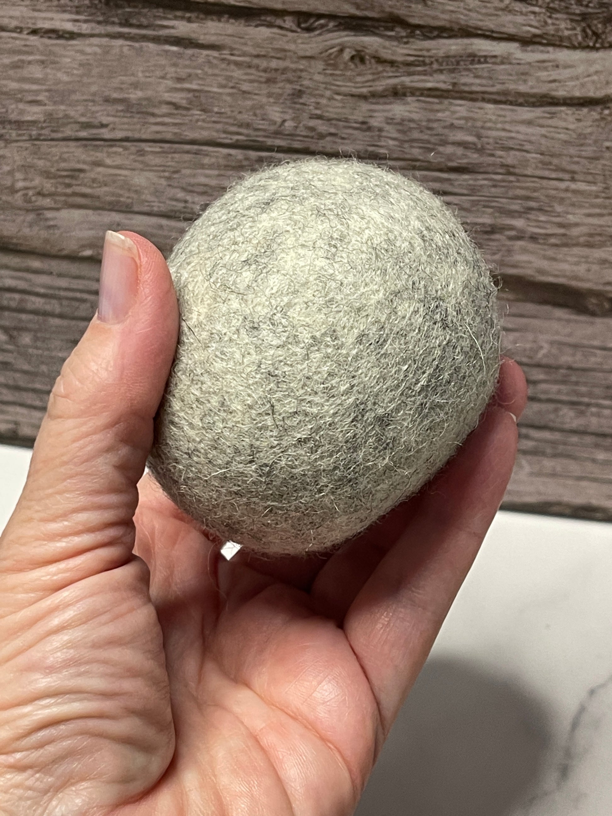 Hand holding a textured gray ball against a wooden surface