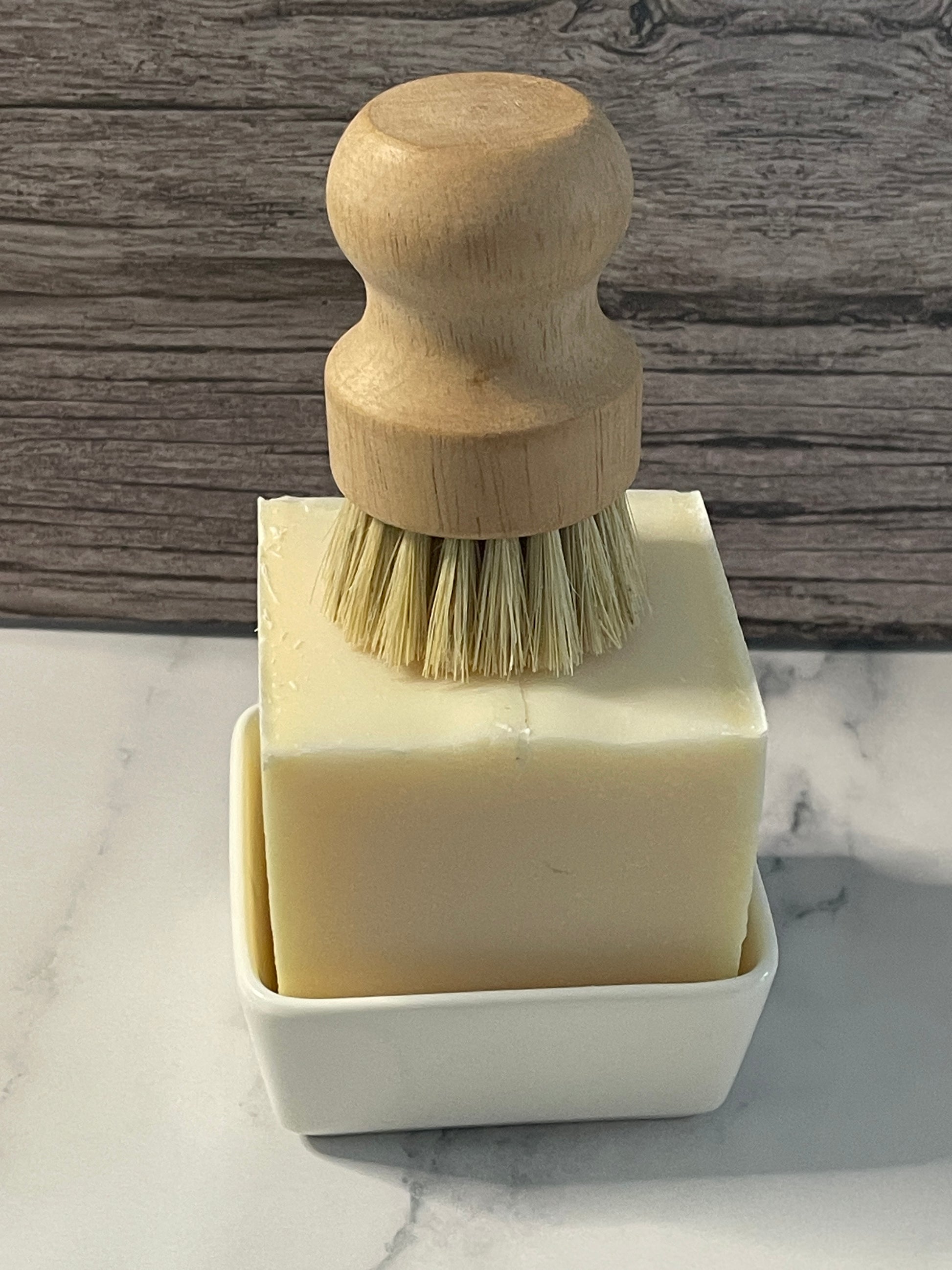 Cleaning brush with wooden handle and white bristles on a marble surface