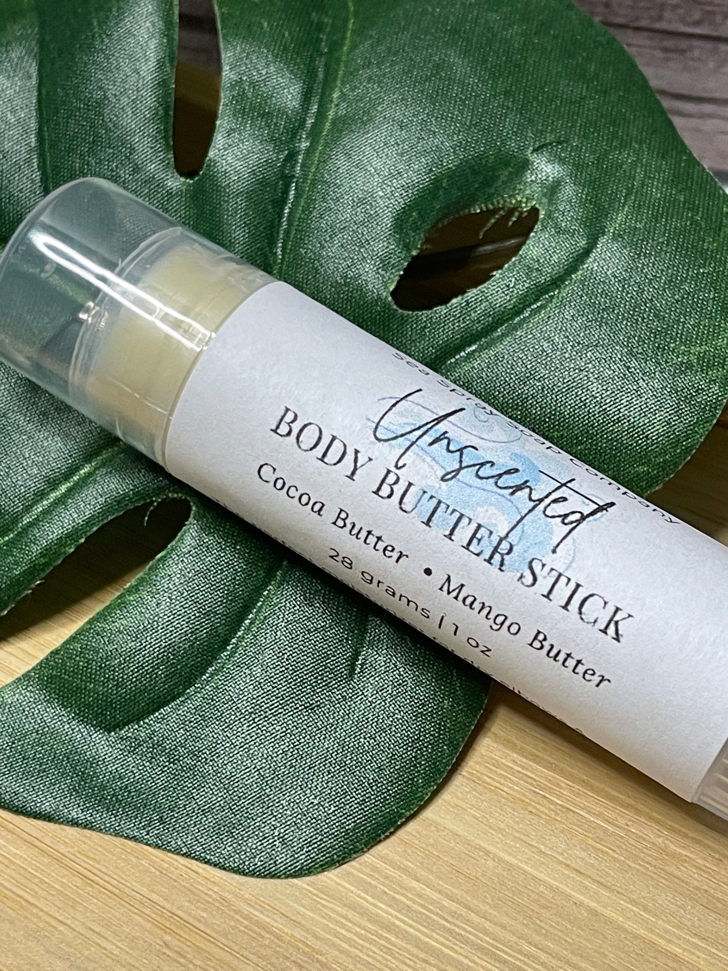 Body butter stick with a green fabric background
