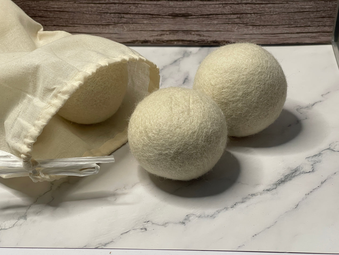 Two white laundry detergent balls on a marble surface with a clear container.