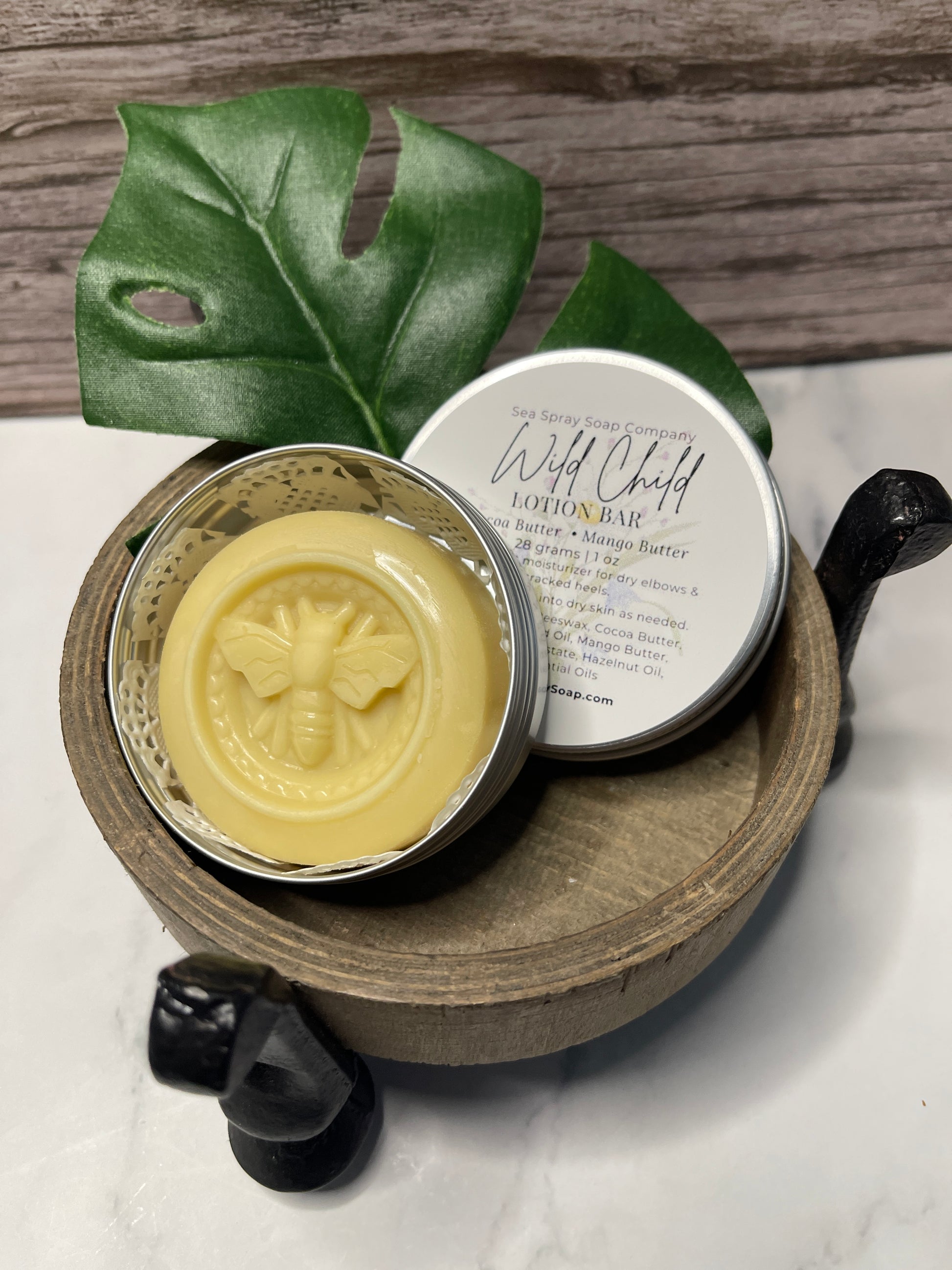 Beeswax product in a wooden container with a green leaf on a wooden surface