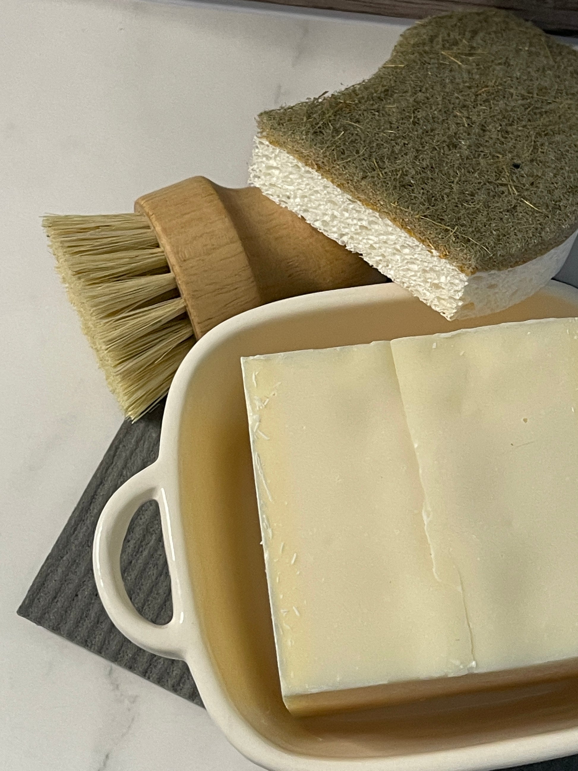 Bar of soap, scrub brush, and loofah on a white surface