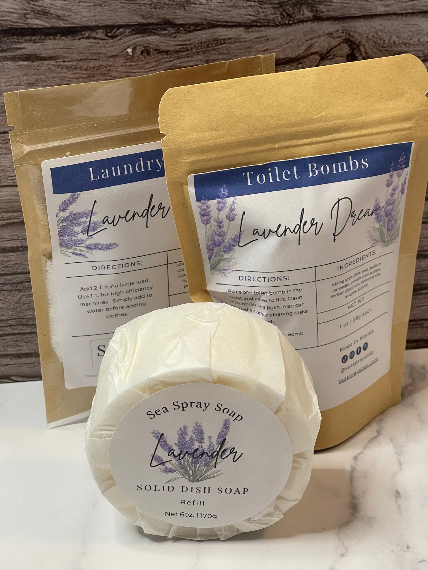 Lavender-themed products including a solid dish bar and laundry soap and toilet bombs on a wooden surface.