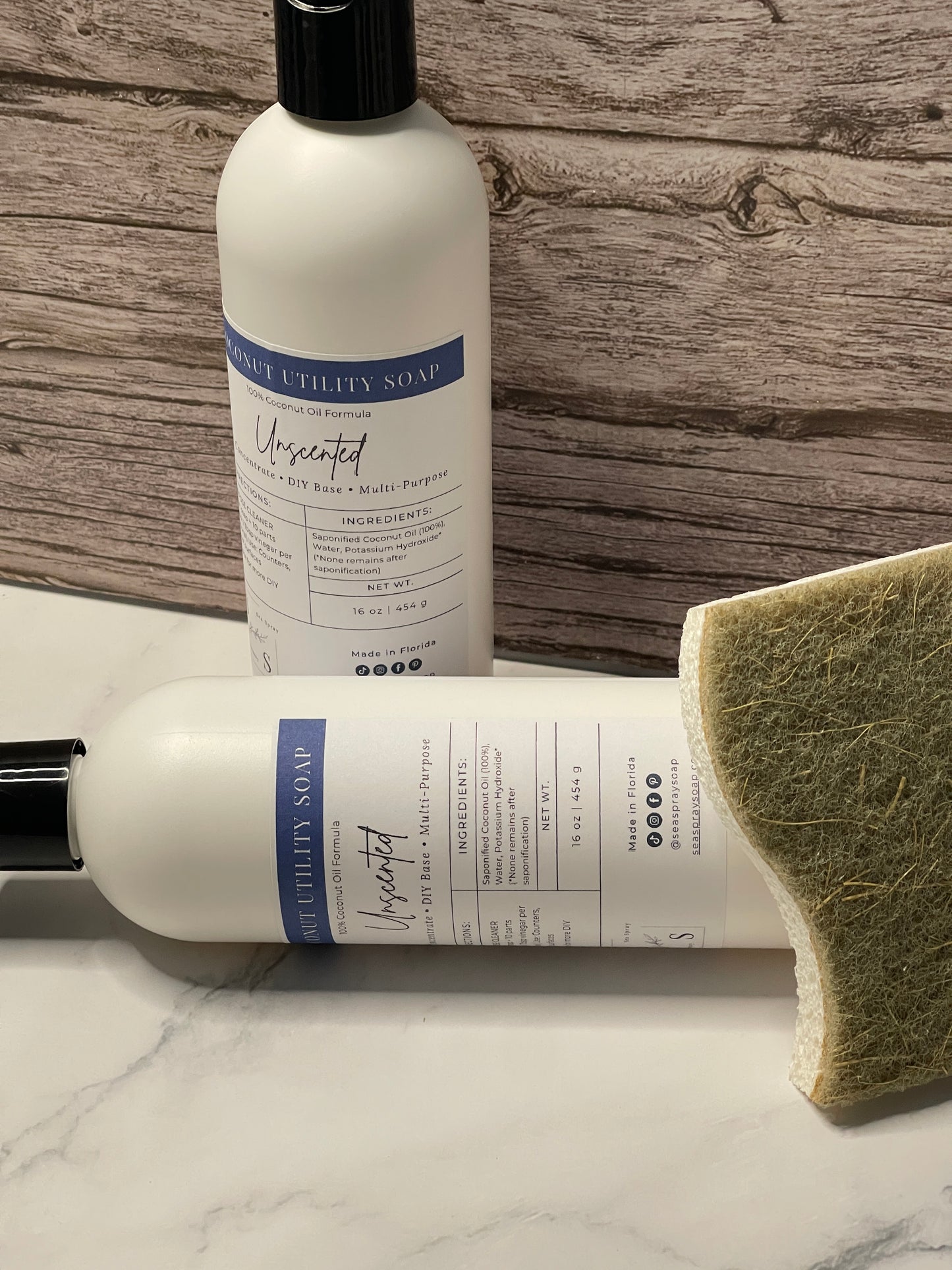 Two bottles of a skincare product with a green sponge on a wooden surface.