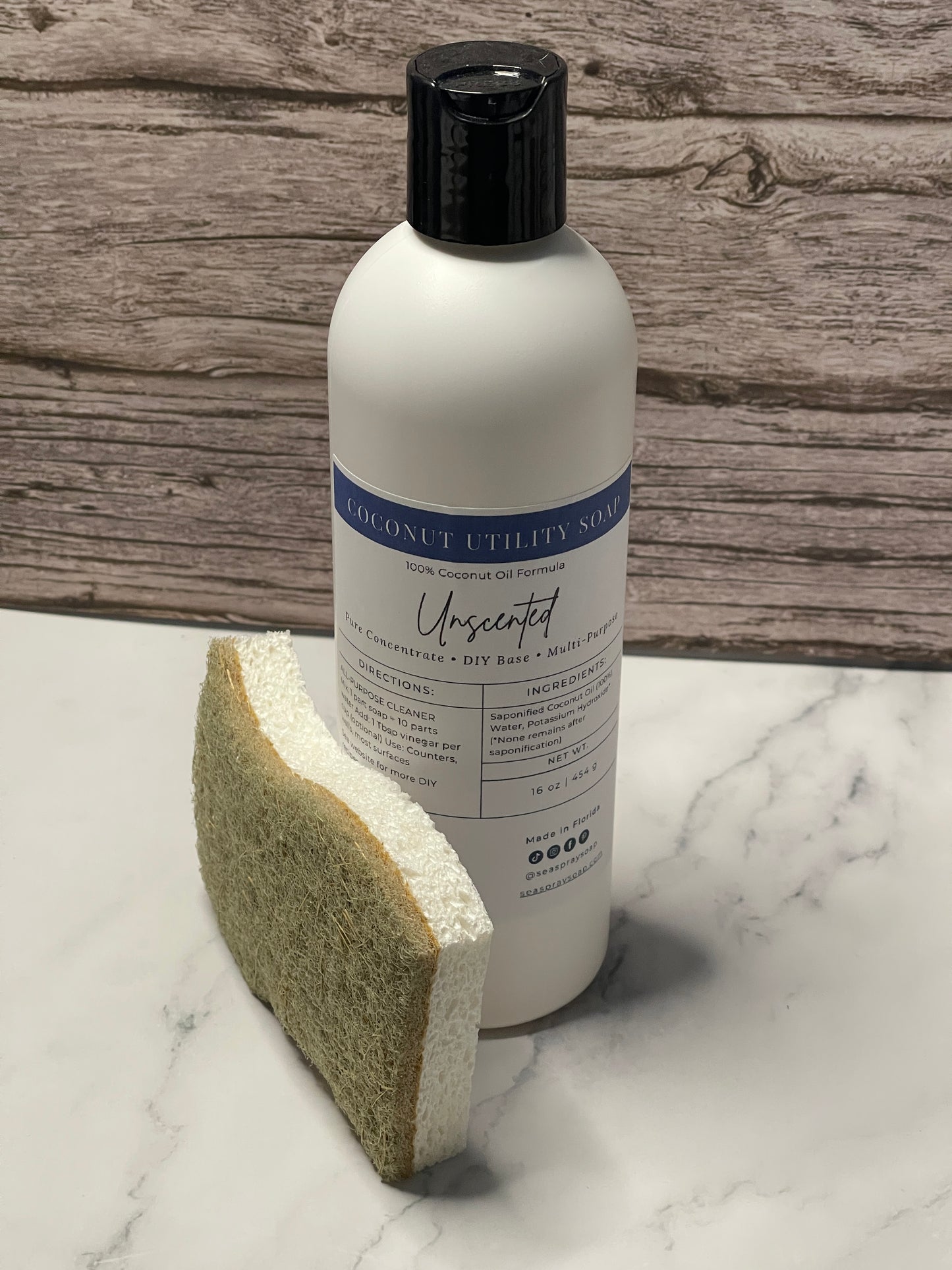 Bottle of Unserver dish soap with a sponge on a marble and wood surface