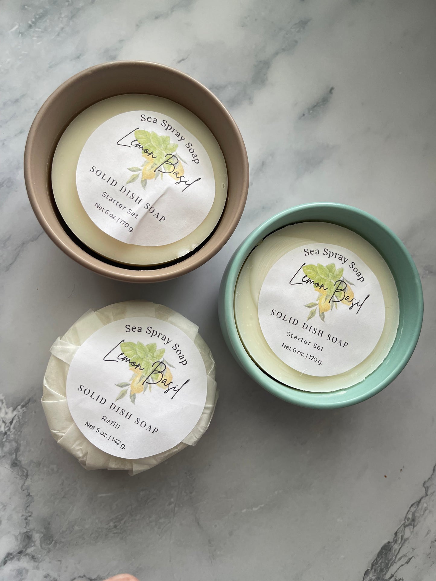 Three bars of soap in containers on a marble surface