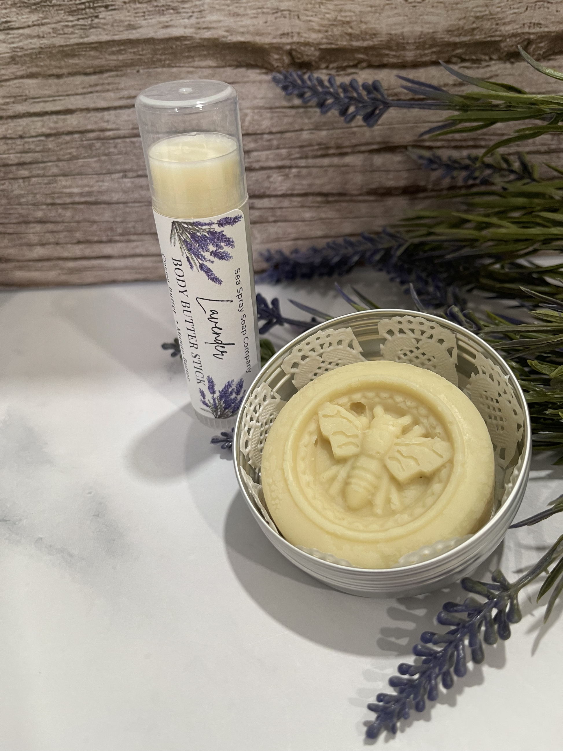 Butterfly-themed soap bar in a decorative container with a lip balm and lavender flowers on a marble surface.