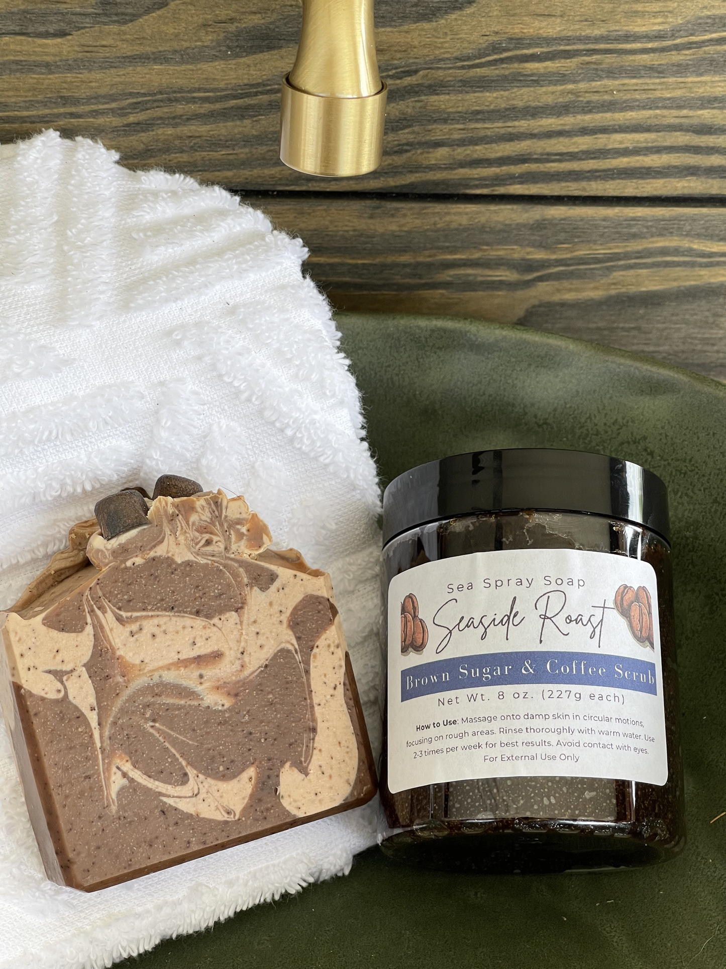 Bar of soap and jar of sea spray soap on a green surface with a towel and faucet in the background.