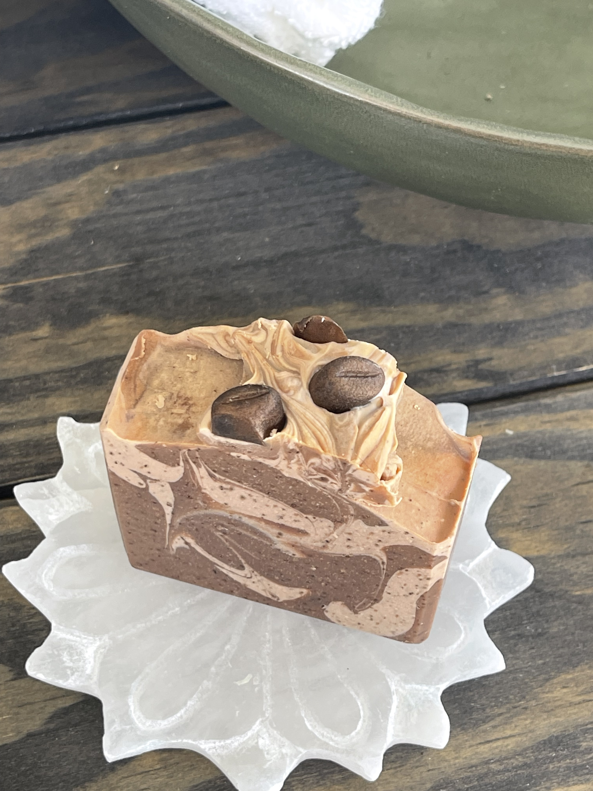 Marbled soap bar with chocolate chips on a white dish, wooden background