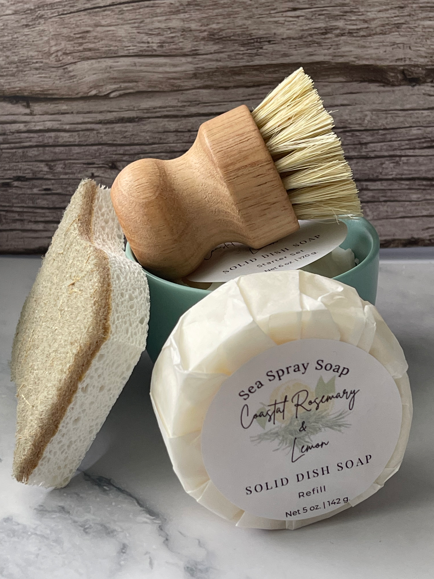Cleaning tools including a brush, sponge, and bar of soap on a wooden surface.