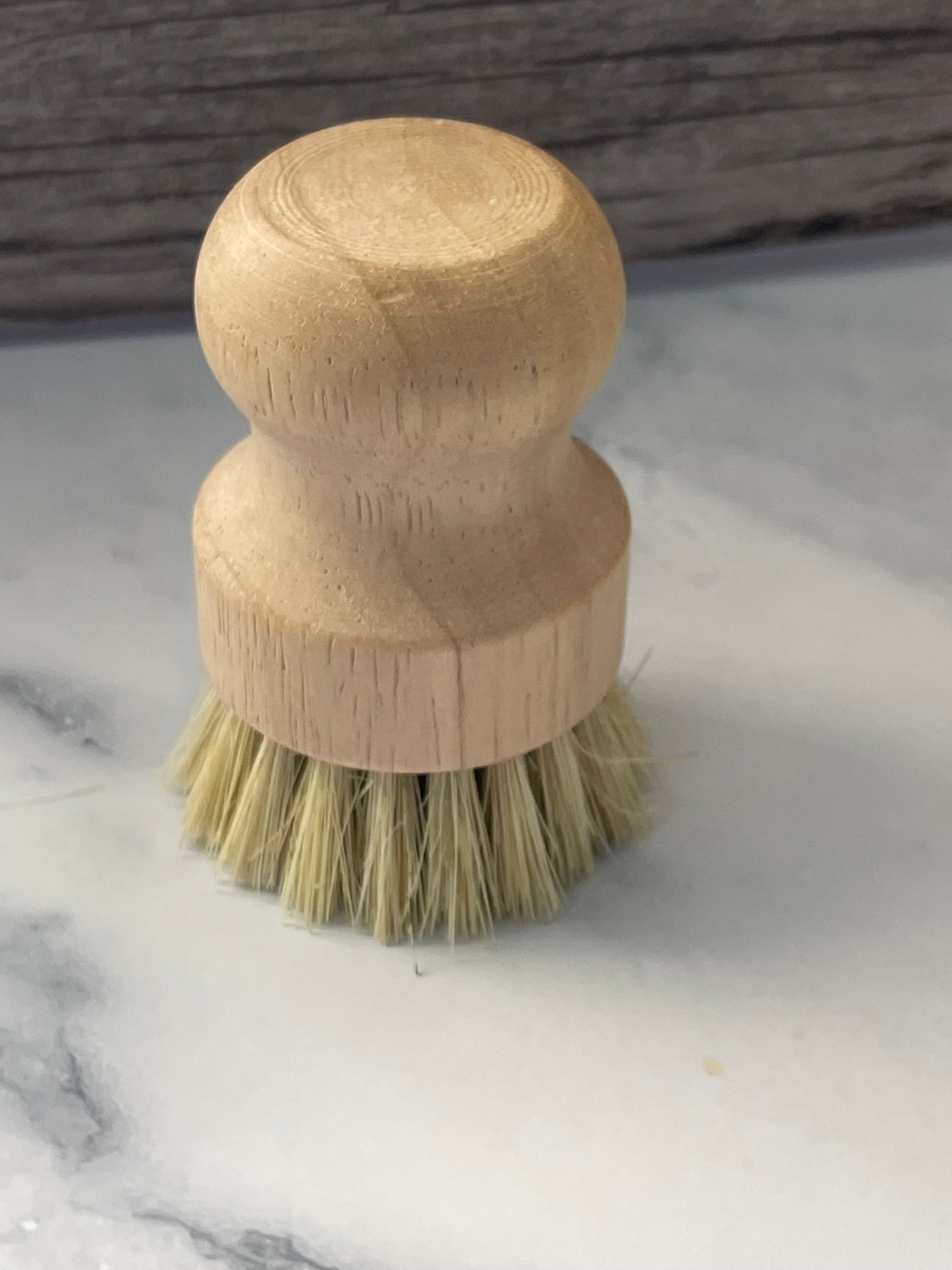 Wooden dish brush with bristle head on a marble surface