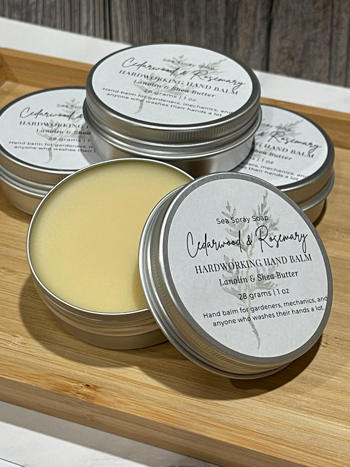 stack of  hardworking hand balm in 2 oz tins with the scent cedarwood and rosemary