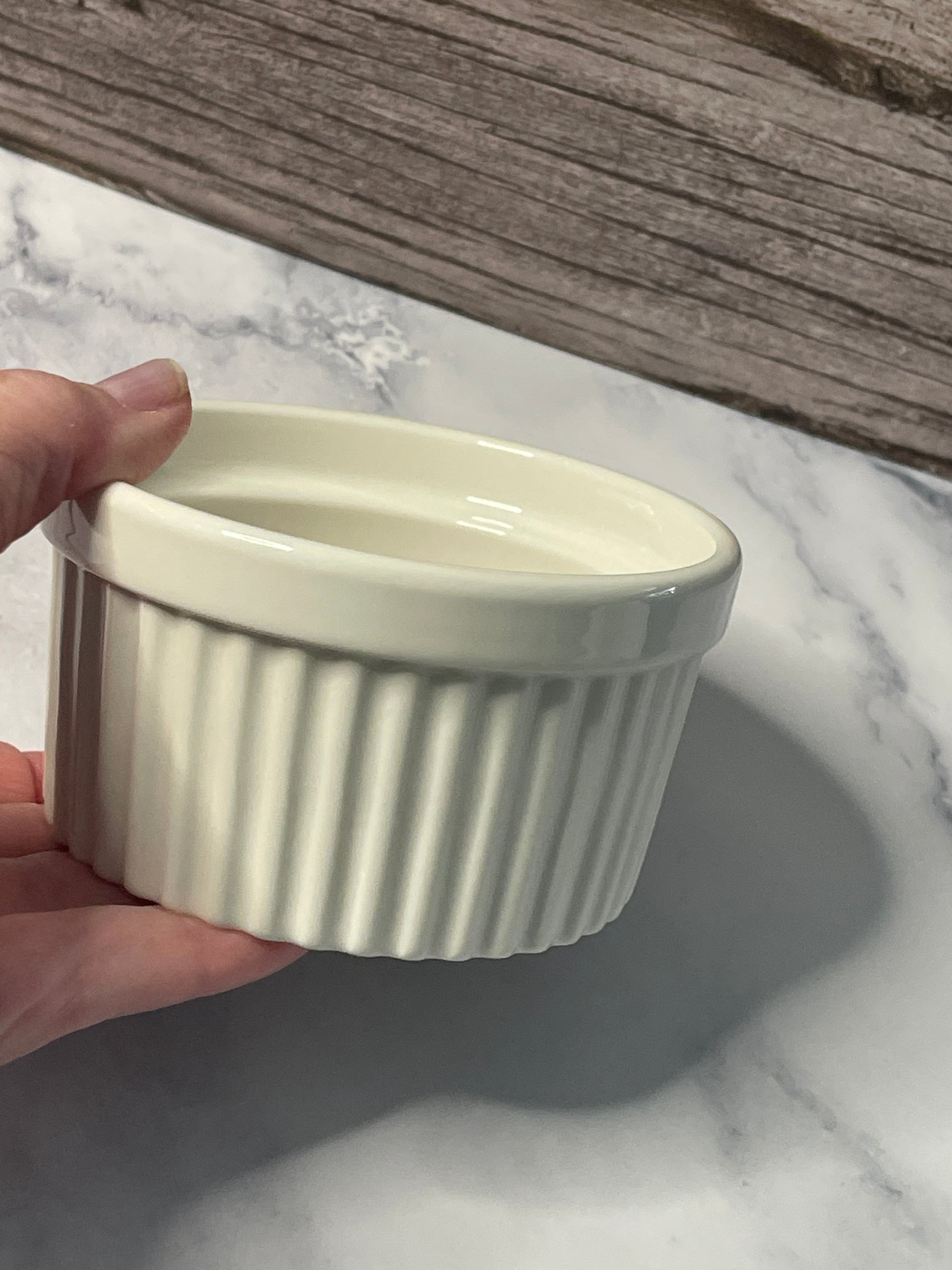 Hand holding a ribbed ceramic bowl on a marble surface