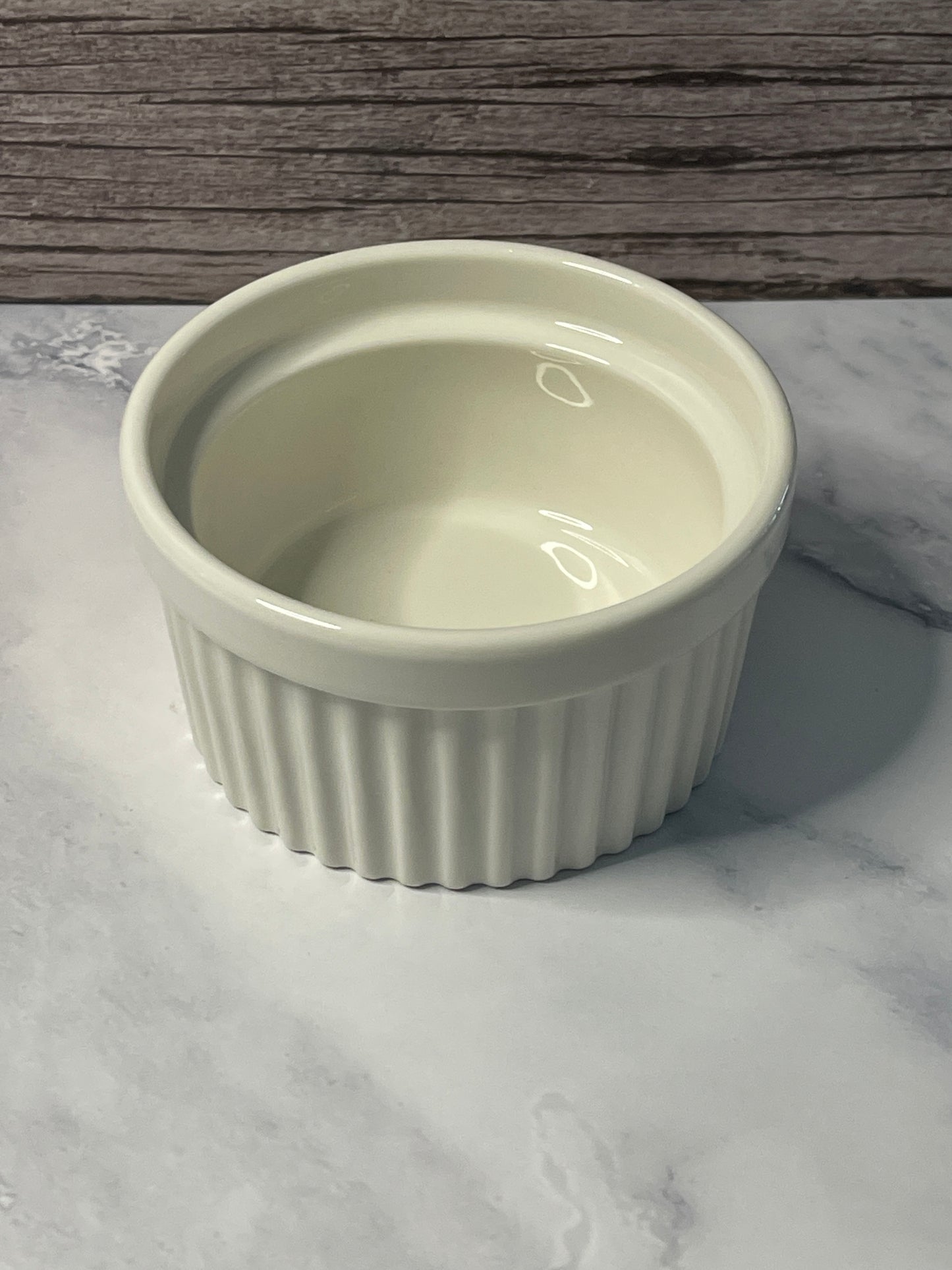 White ribbed ramekin on a marble surface