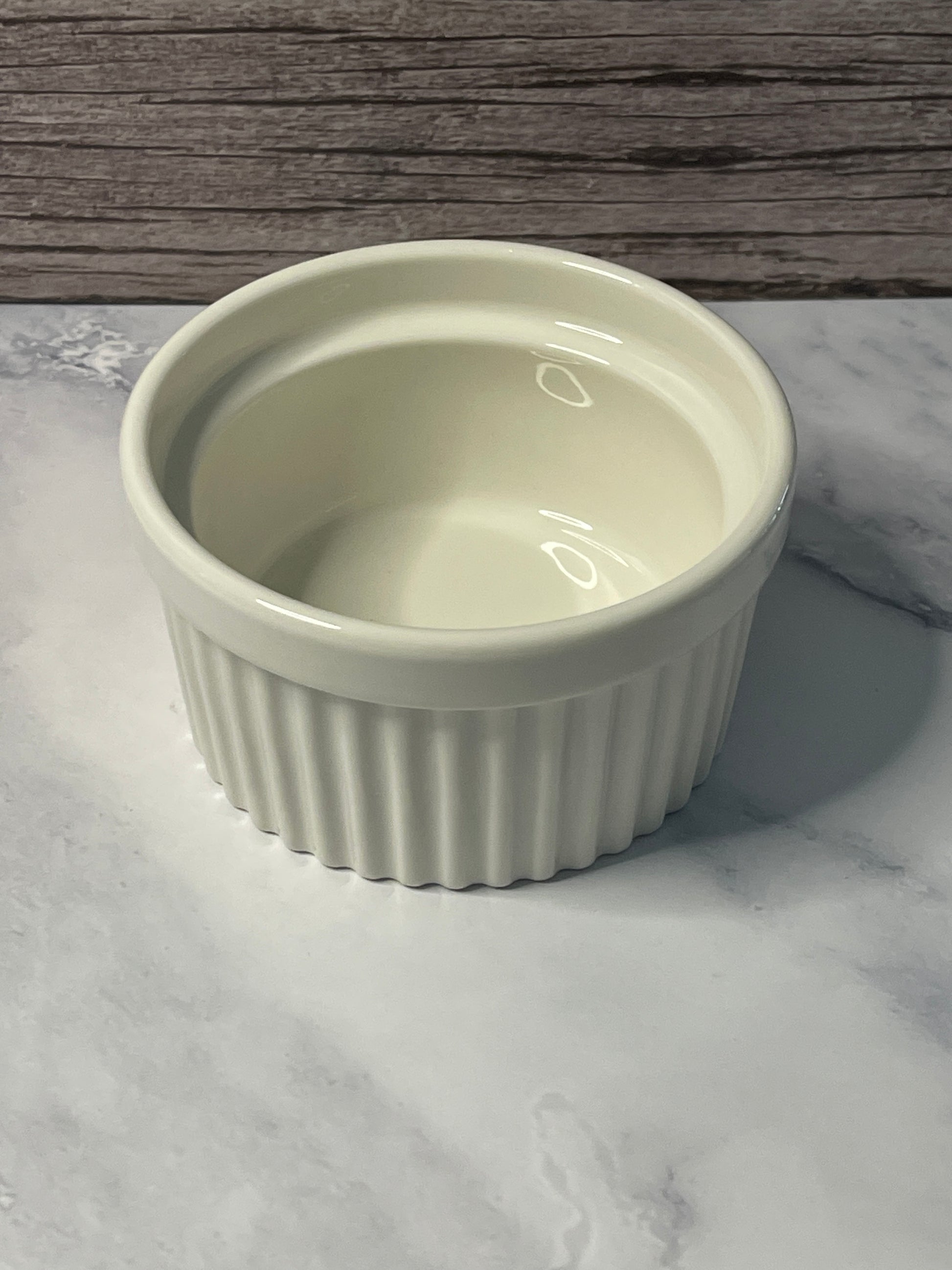 White ribbed ramekin on a marble surface