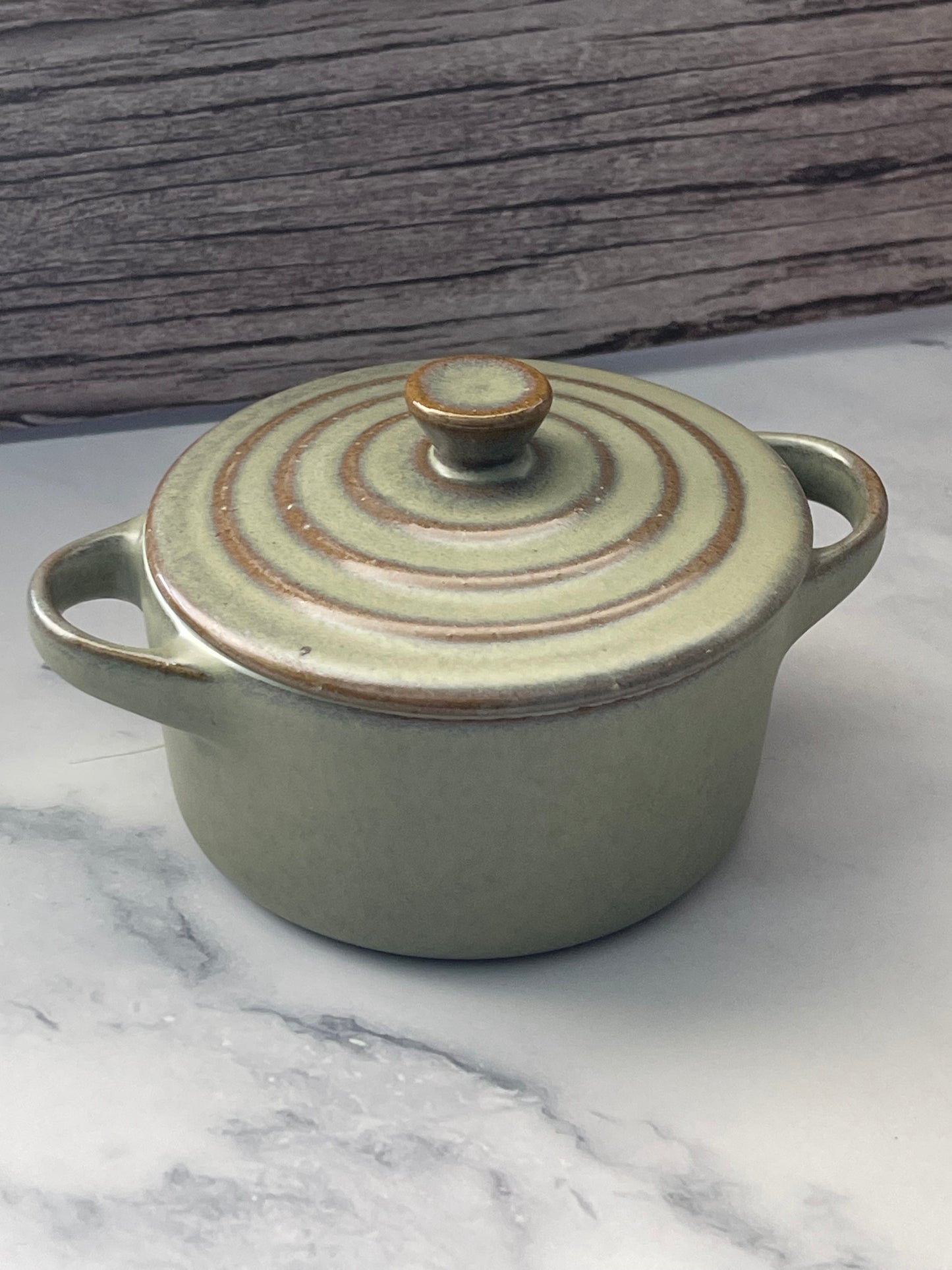 Small ceramic pot with lid on a marble surface