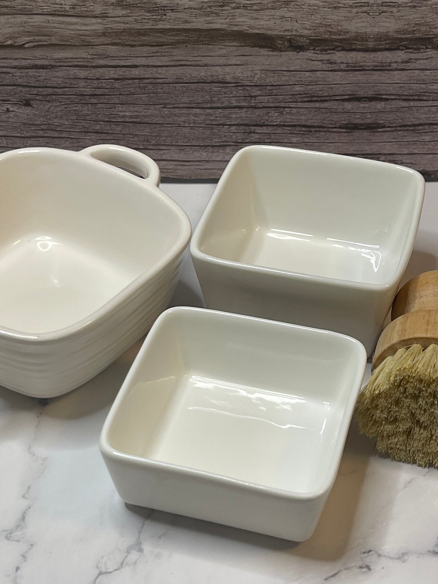 Three white ceramic bowls on a marble surface with a wooden background