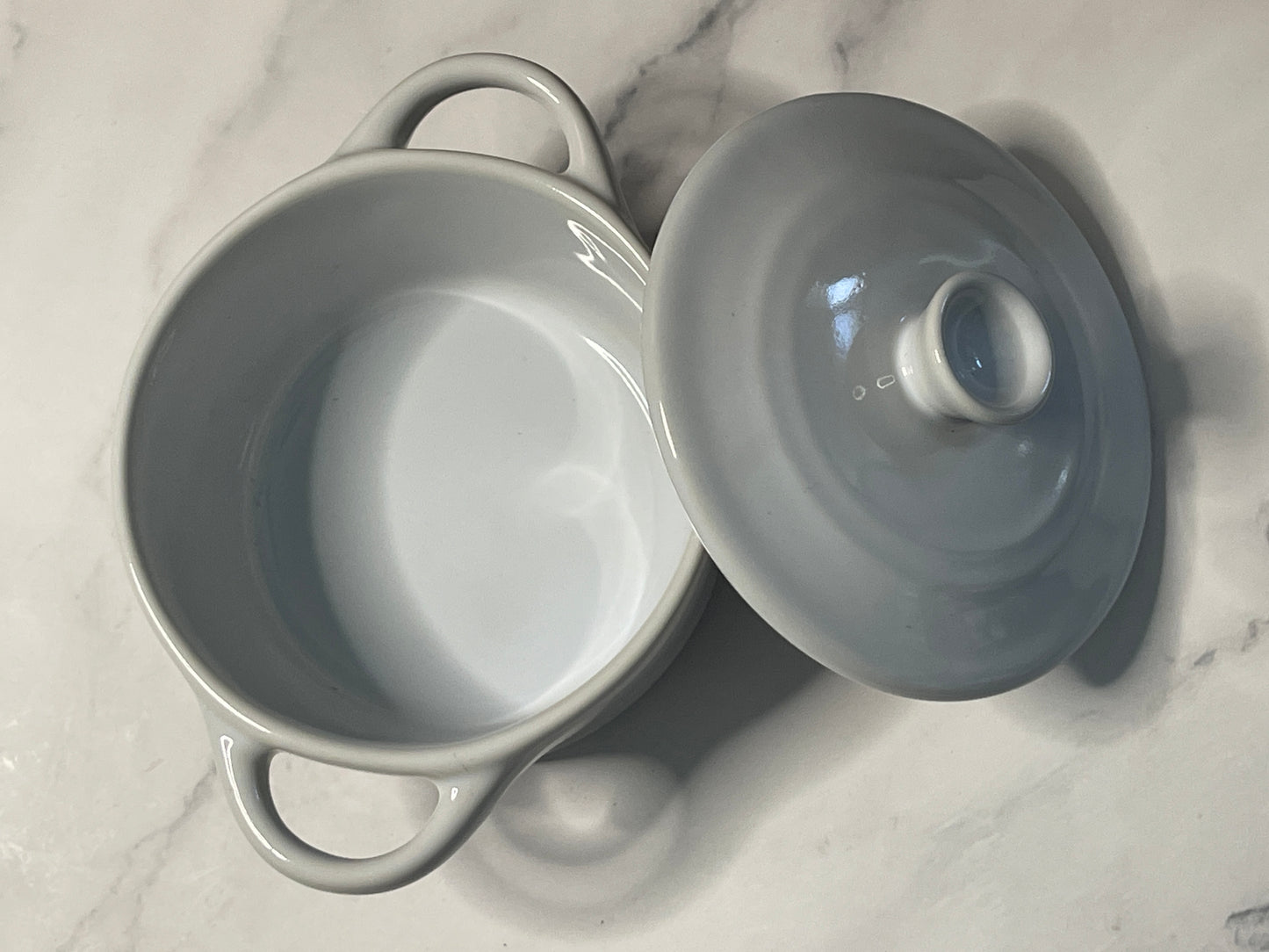 White ceramic pot with lid on a marble surface