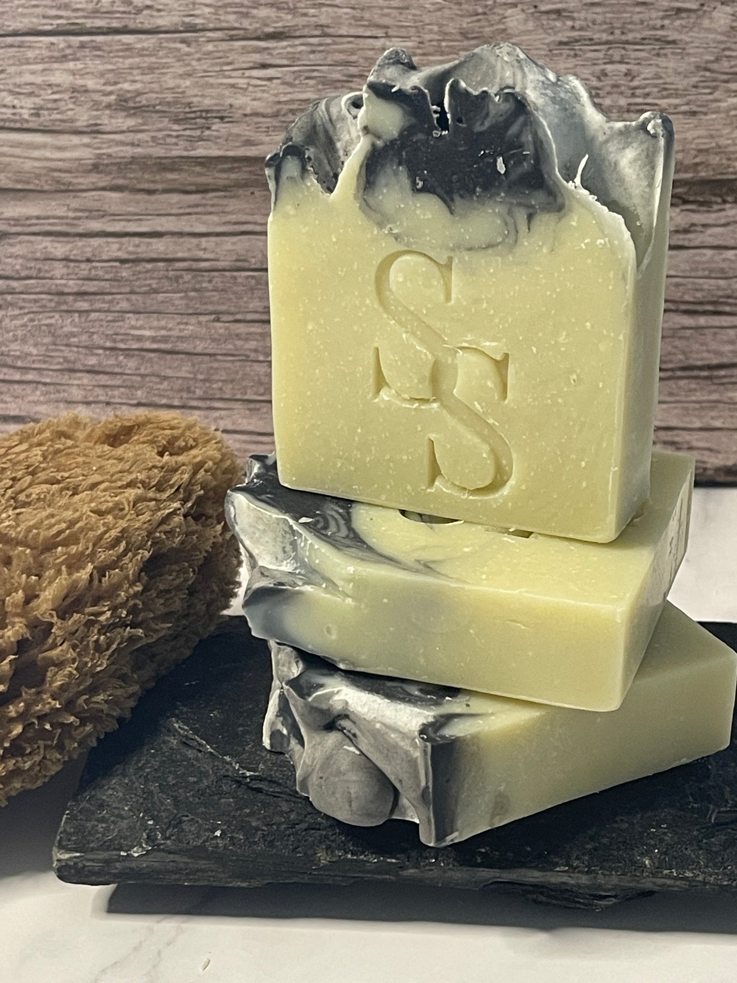 Three bars of soap with a logo on a wooden surface
