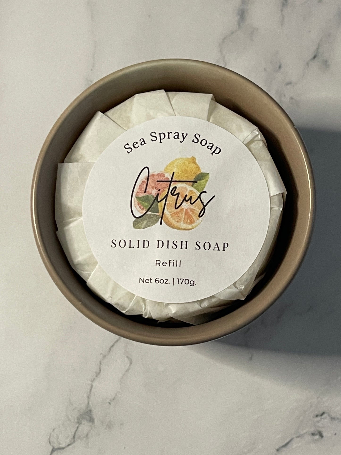 Solid dish soap bar in a container with a label on a marble surface