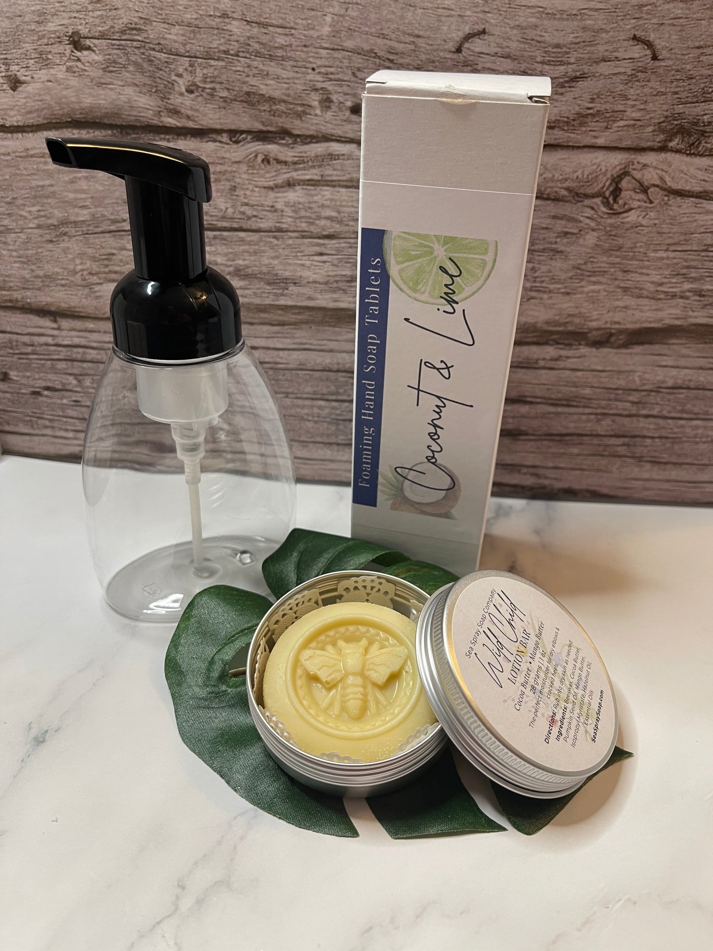 Hand soap dispenser, soap bar, and container on a marble surface with a wooden background